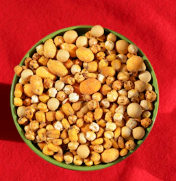 A green bowl filled with corn on top of a red cloth