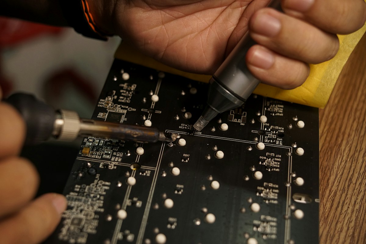 Close up of a technician working on a multilayer circuit board with visible via holes