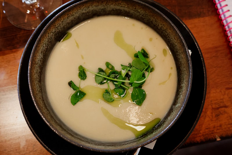 A steaming bowl of rustic soup on a wooden table