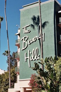 A sign for the beverly hills hotel with palm trees in the background