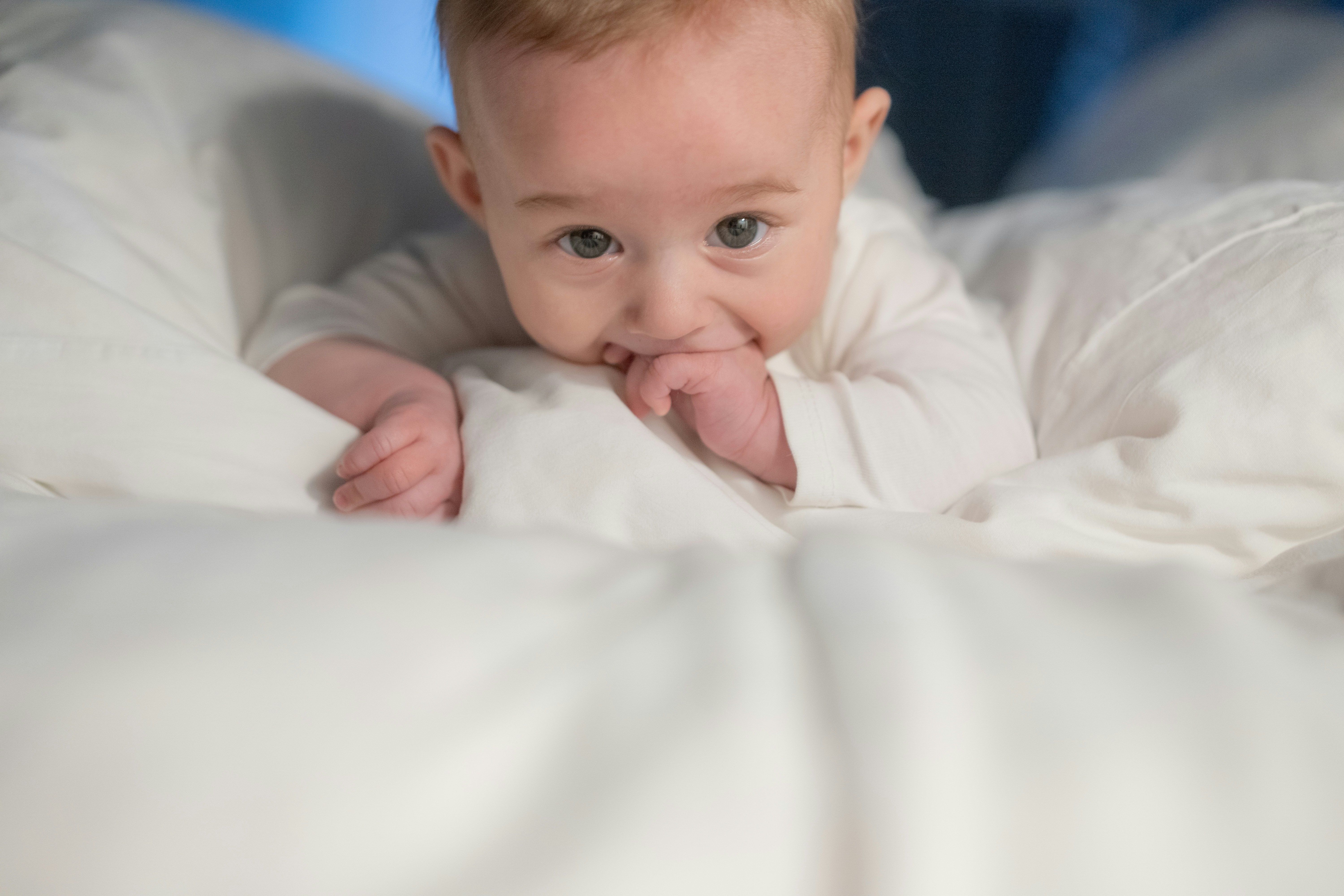 A baby laying on a bed with white sheets