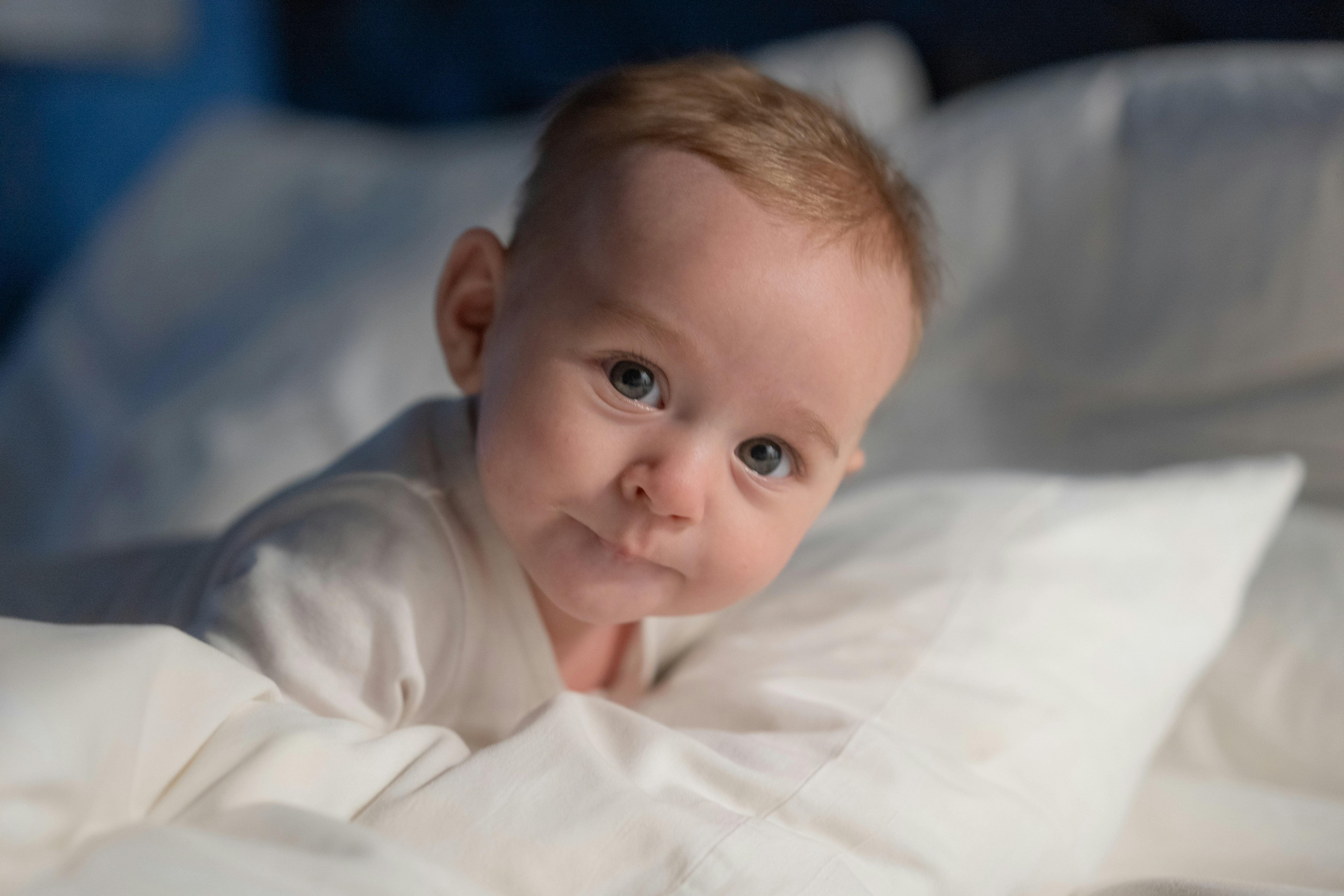 A baby laying in a bed with white sheets