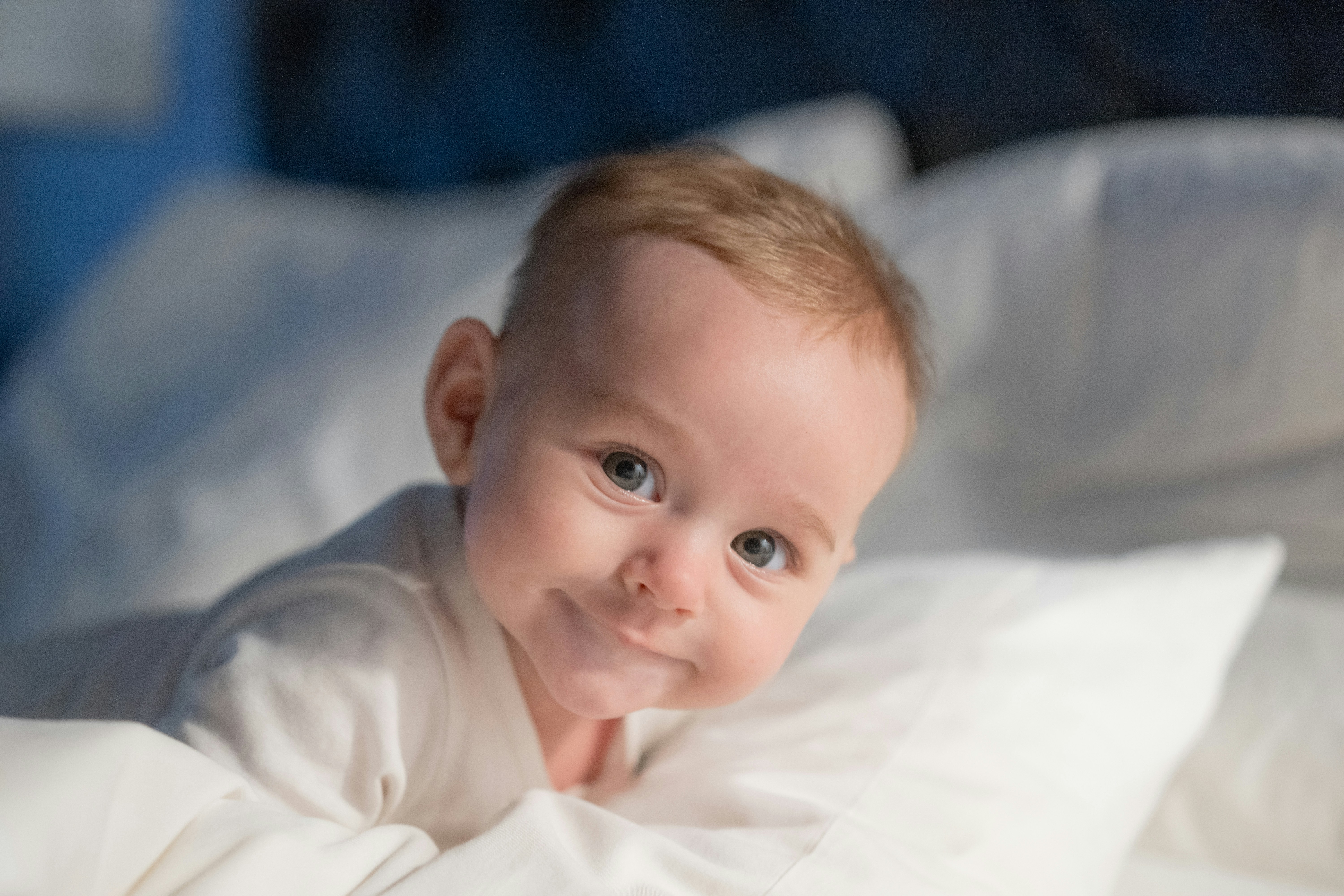 A baby laying on a bed with white sheets