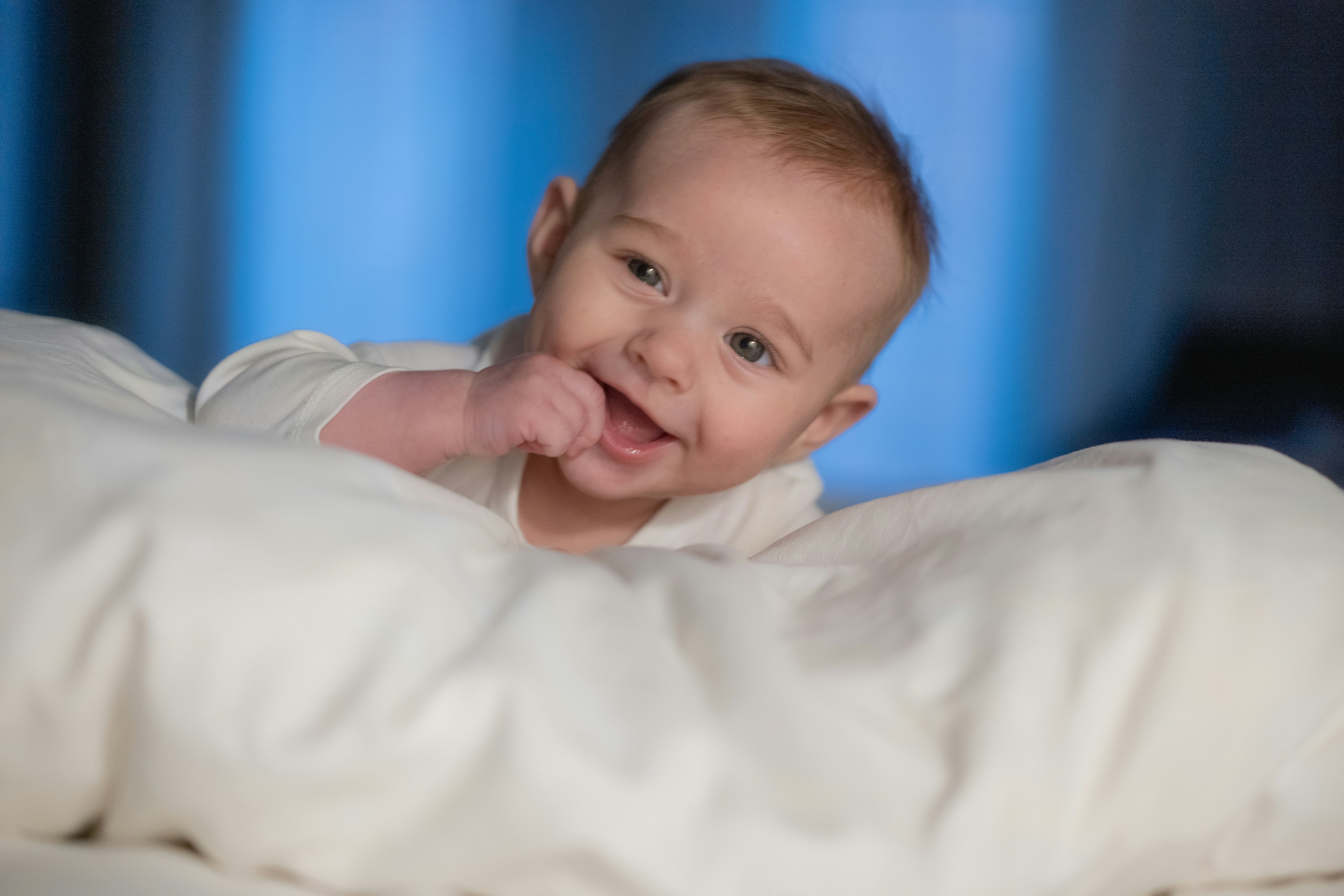 A baby laying on a bed with a white blanket