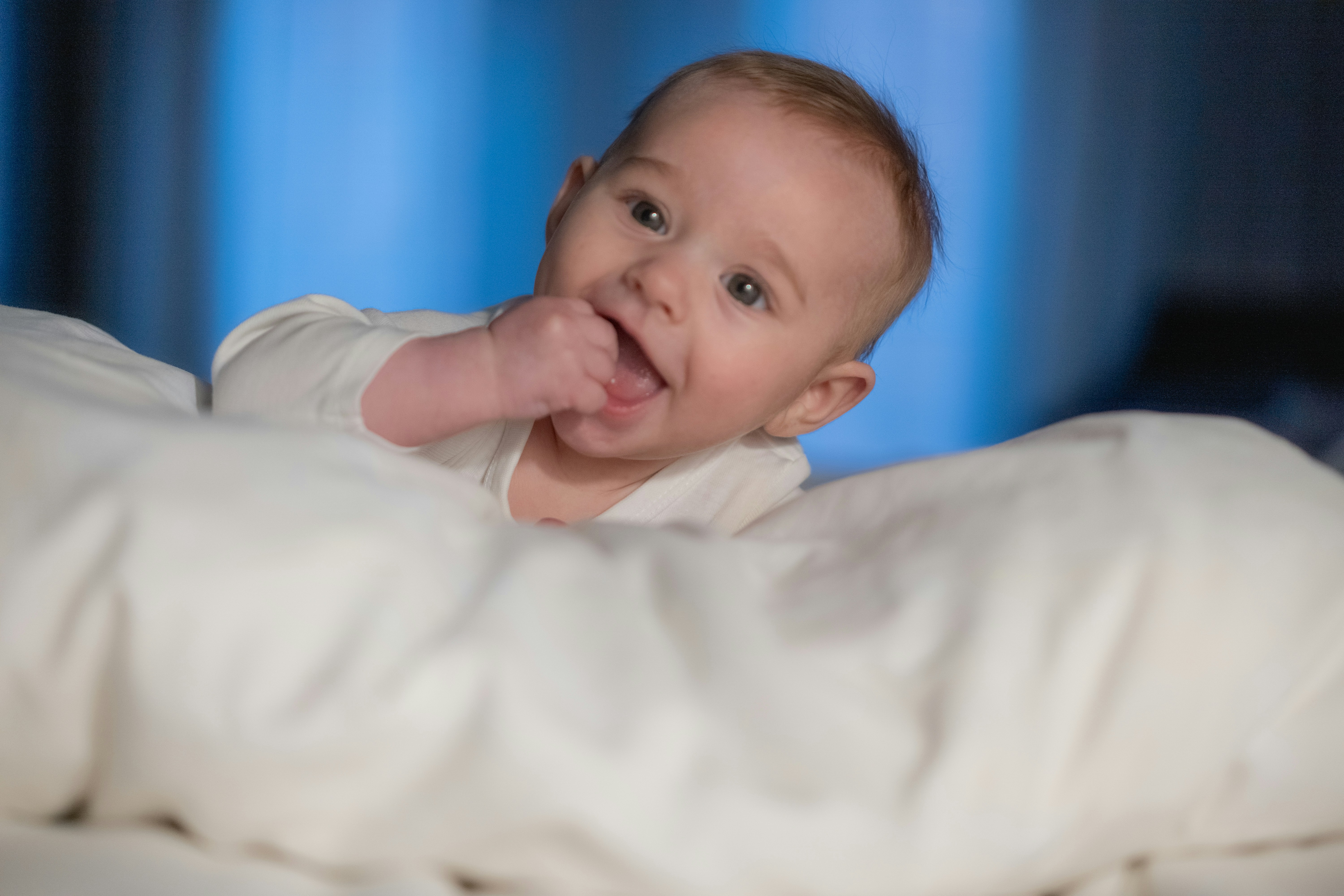 A baby laying in a bed with a white blanket