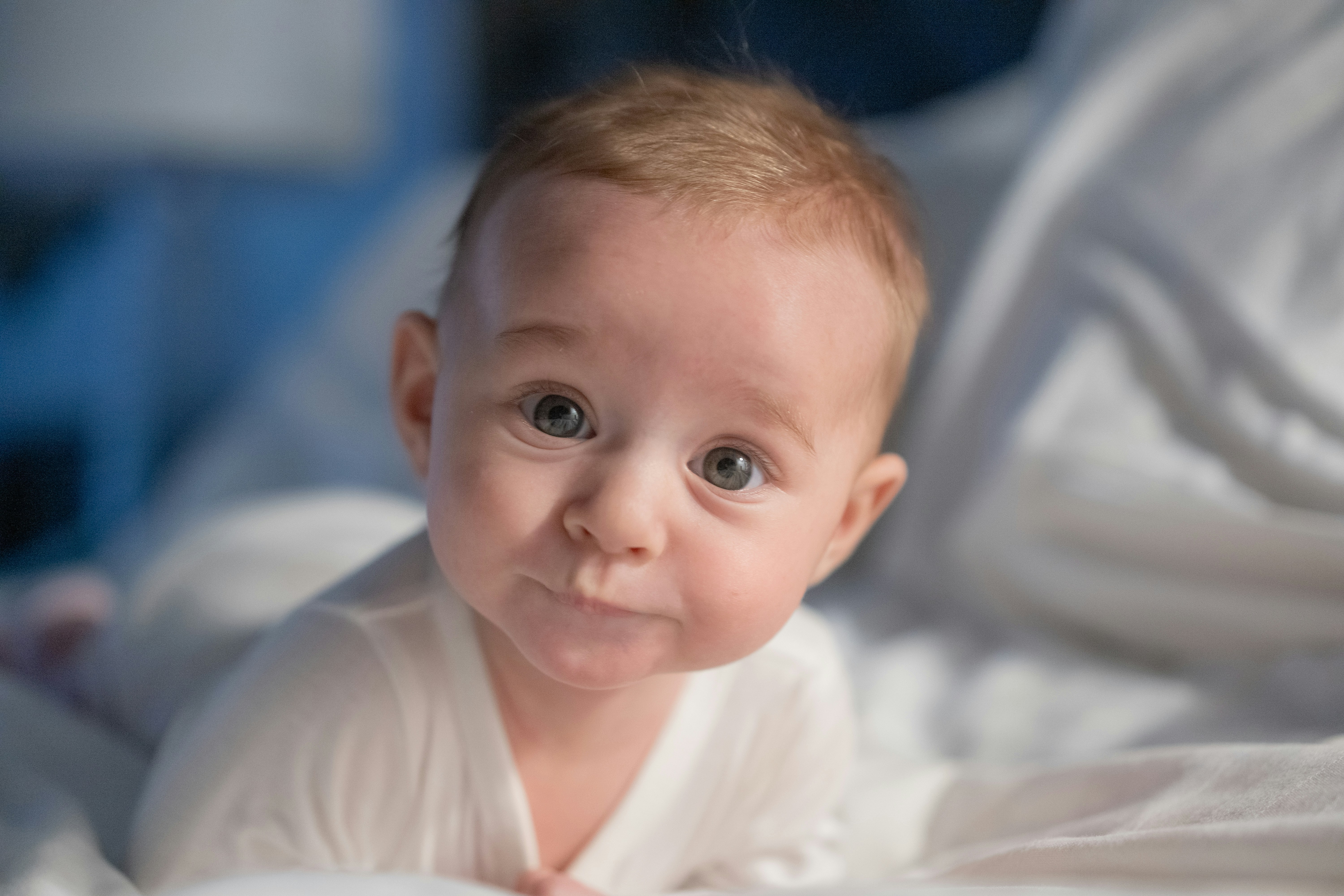 A baby laying on a bed with white sheets