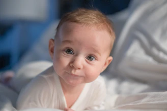 A baby laying on a bed with white sheets
