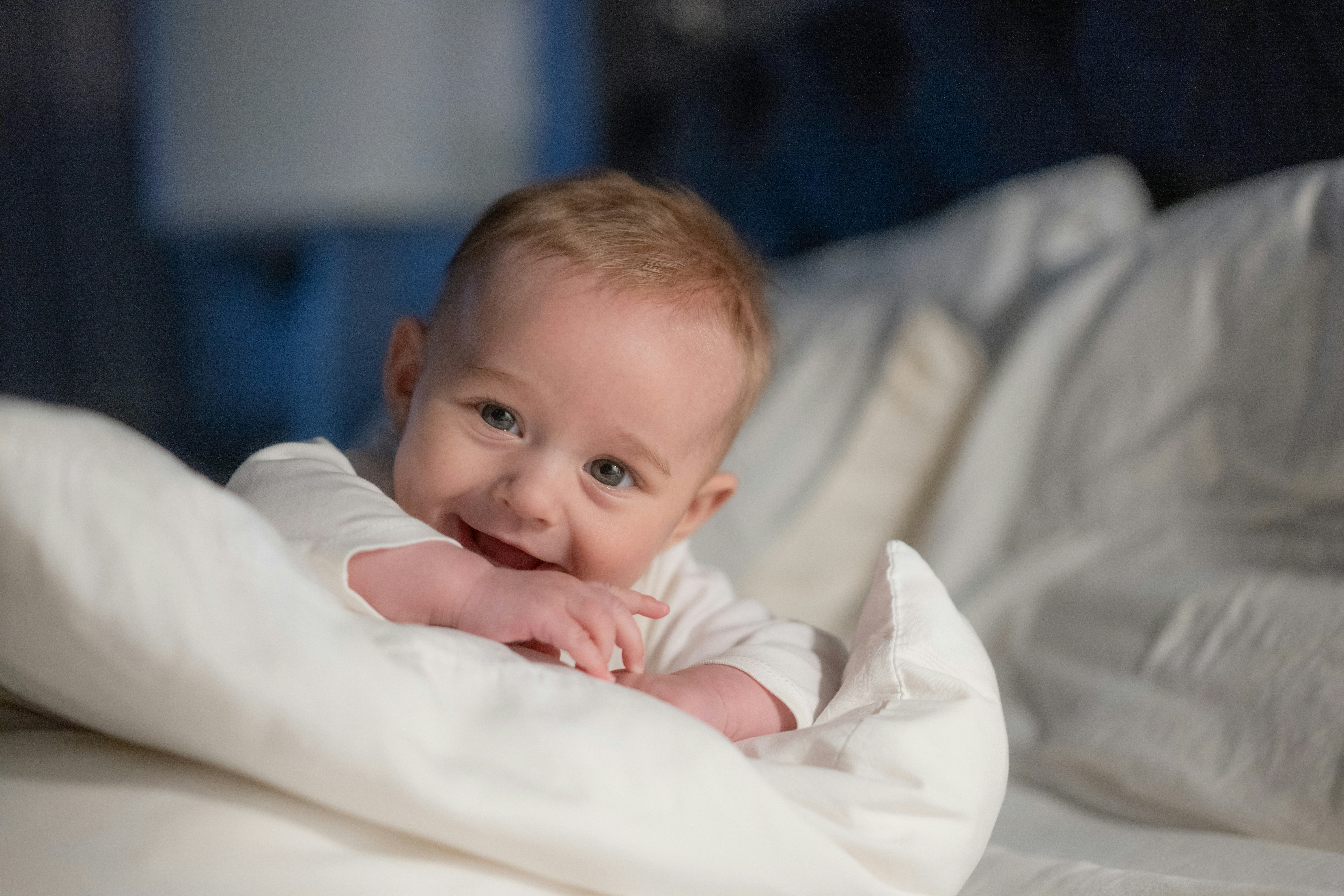 A baby laying on a bed with a white blanket