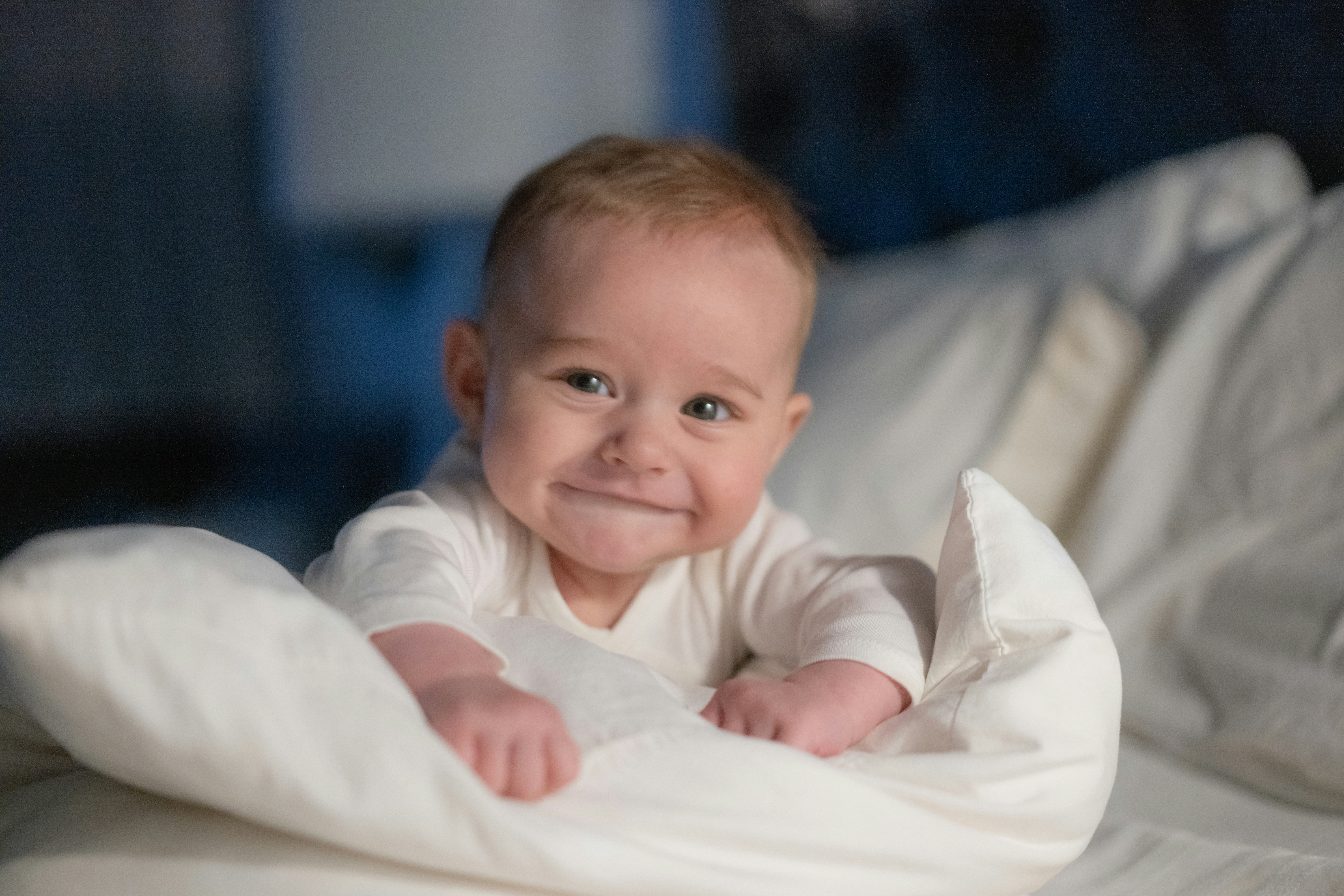 A baby laying on top of a bed covered in a blanket