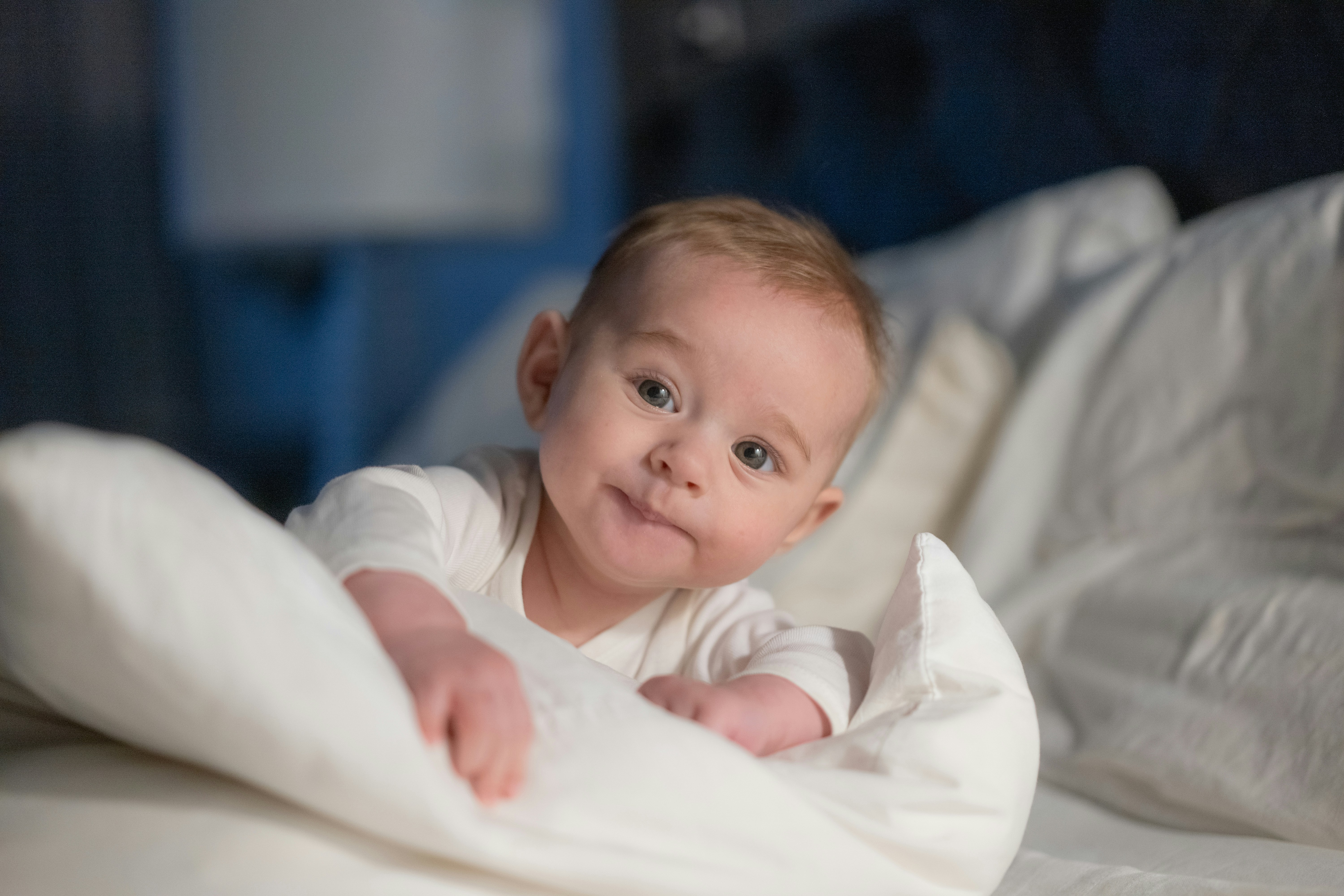 A baby laying on a bed under a blanket