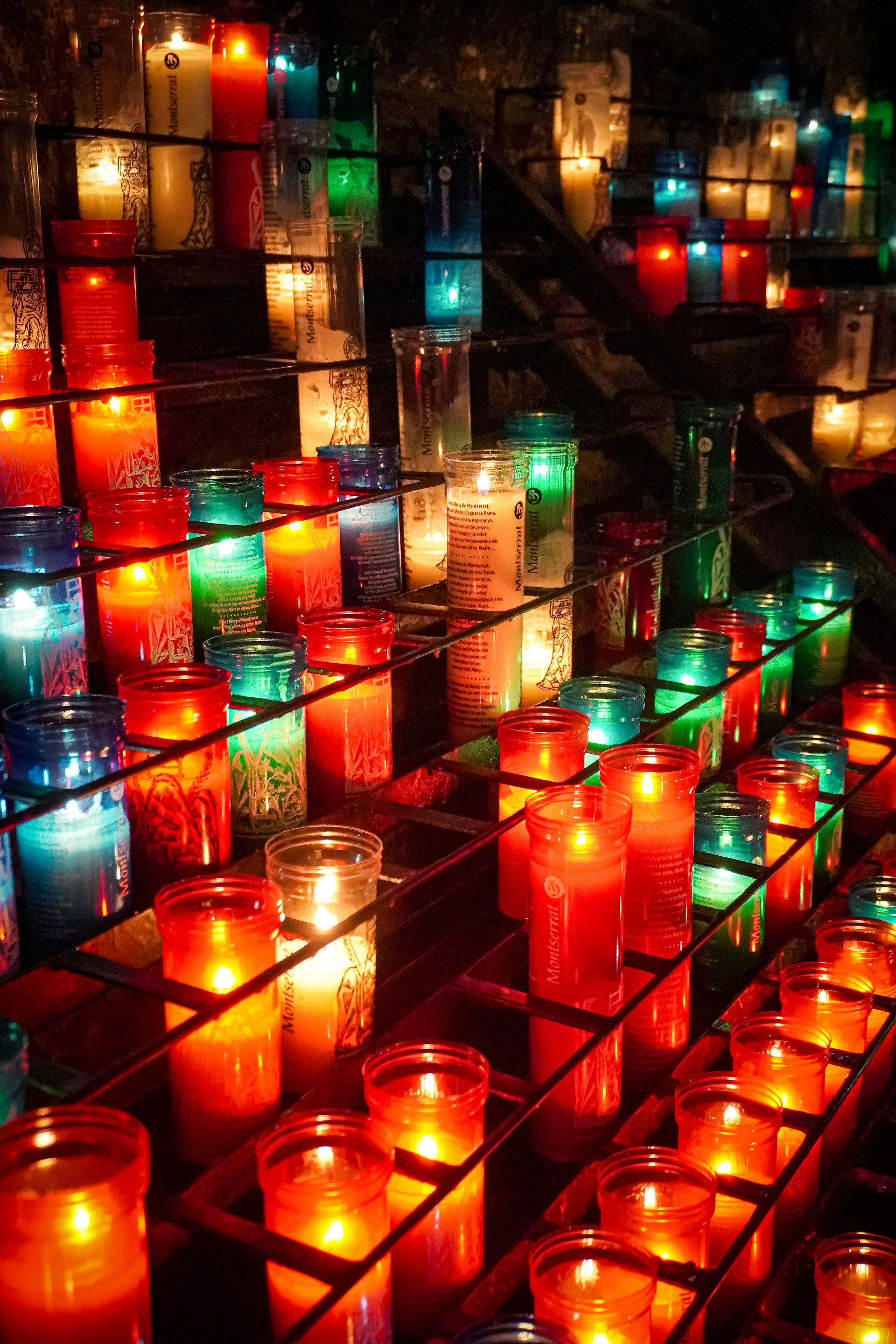 Many lit candles are arranged in rows on a table