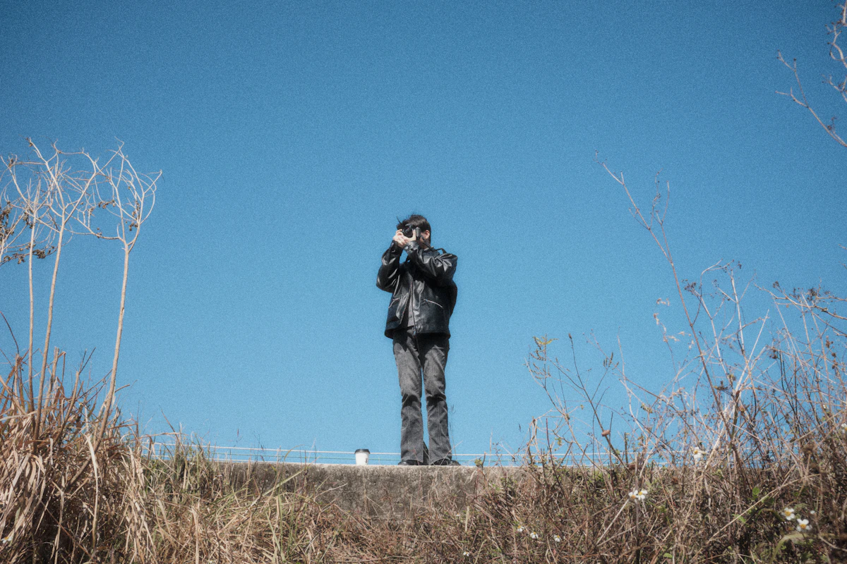 A man standing on top of a hill with a camera