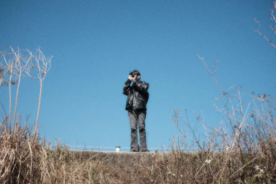 A man standing on top of a hill with a camera