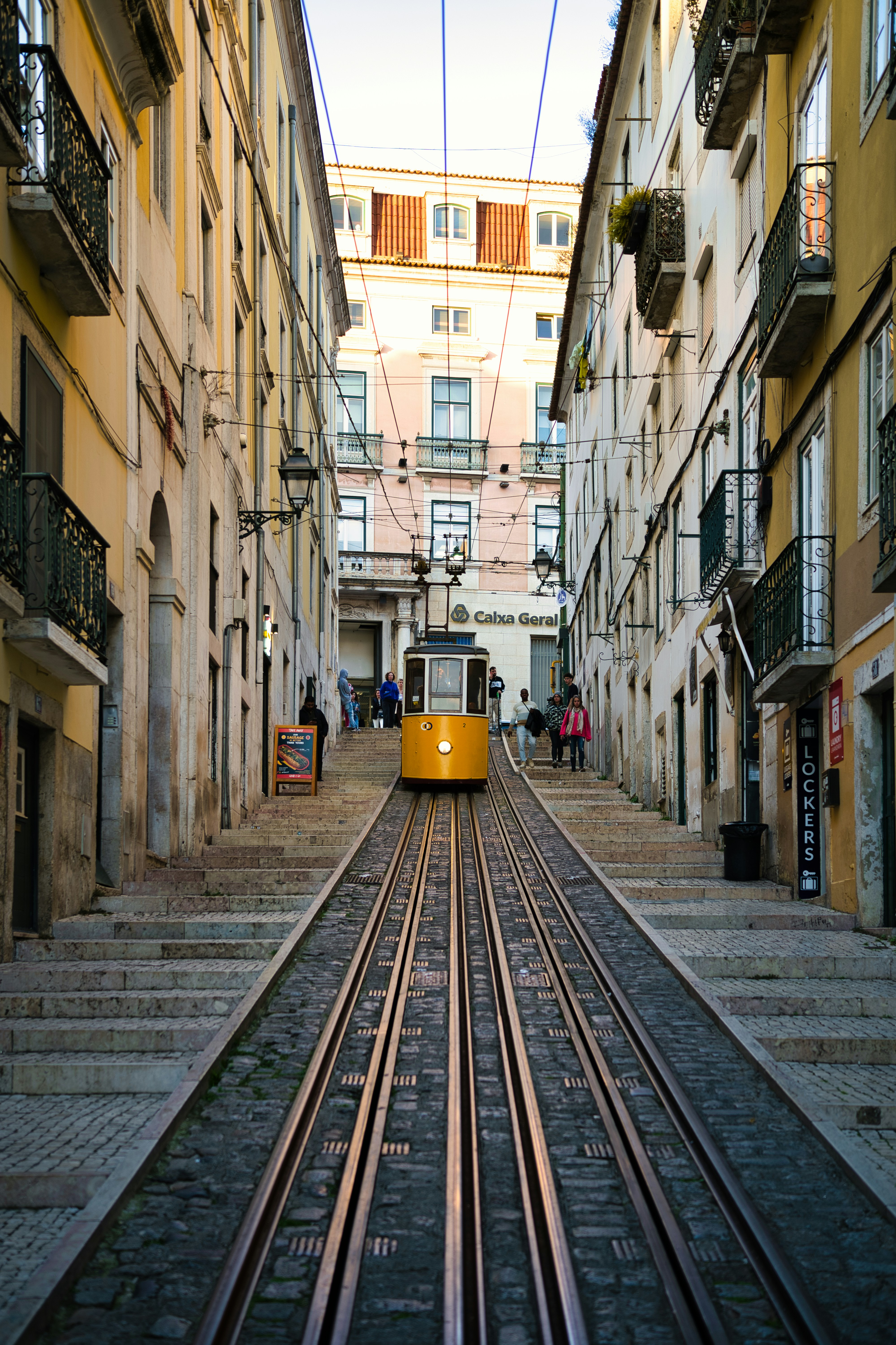 Yellow tram passing colorful buildings on a steep Lisbon street