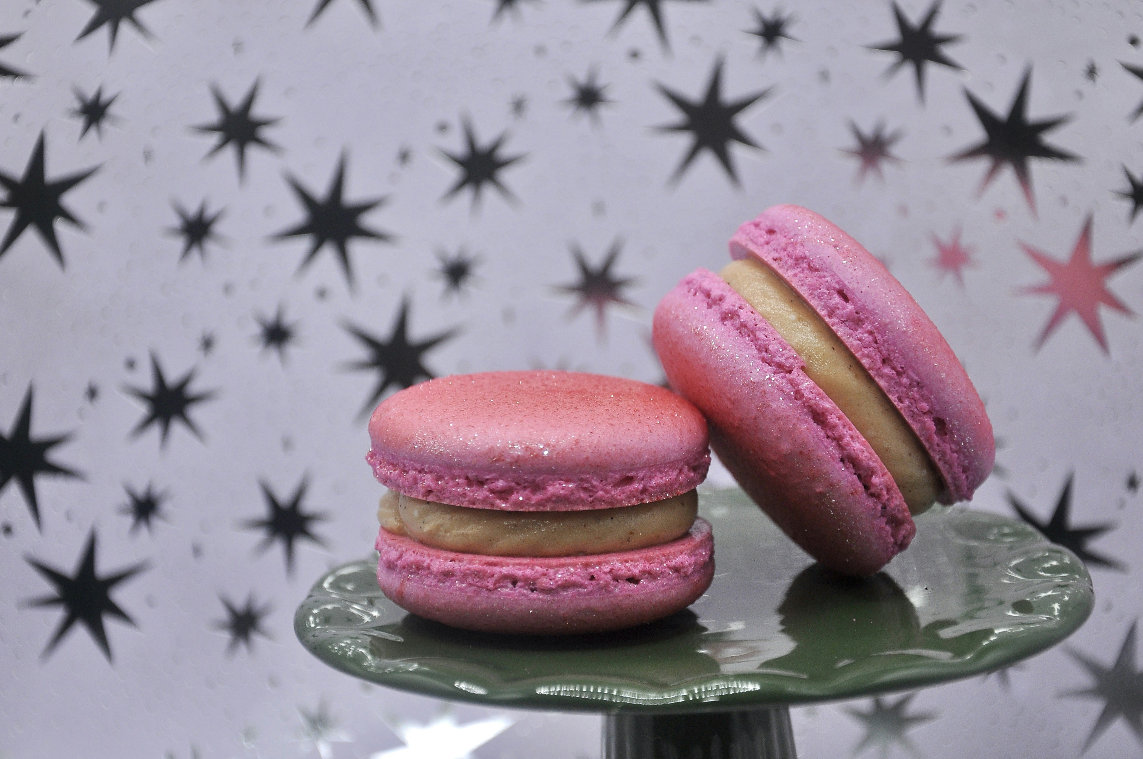 A couple of pink macaroons sitting on top of a green plate