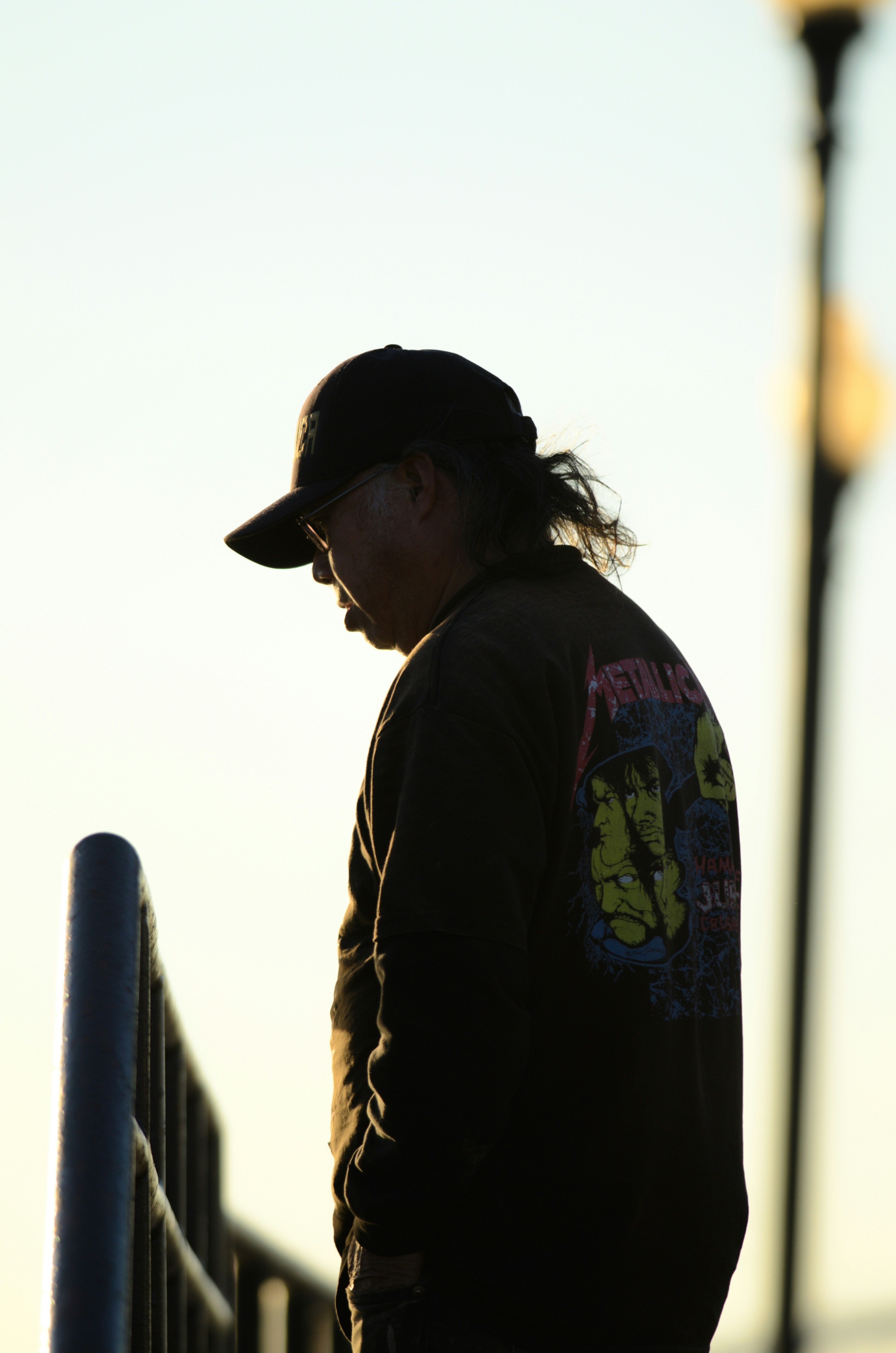 A man standing next to a fence with a skateboard