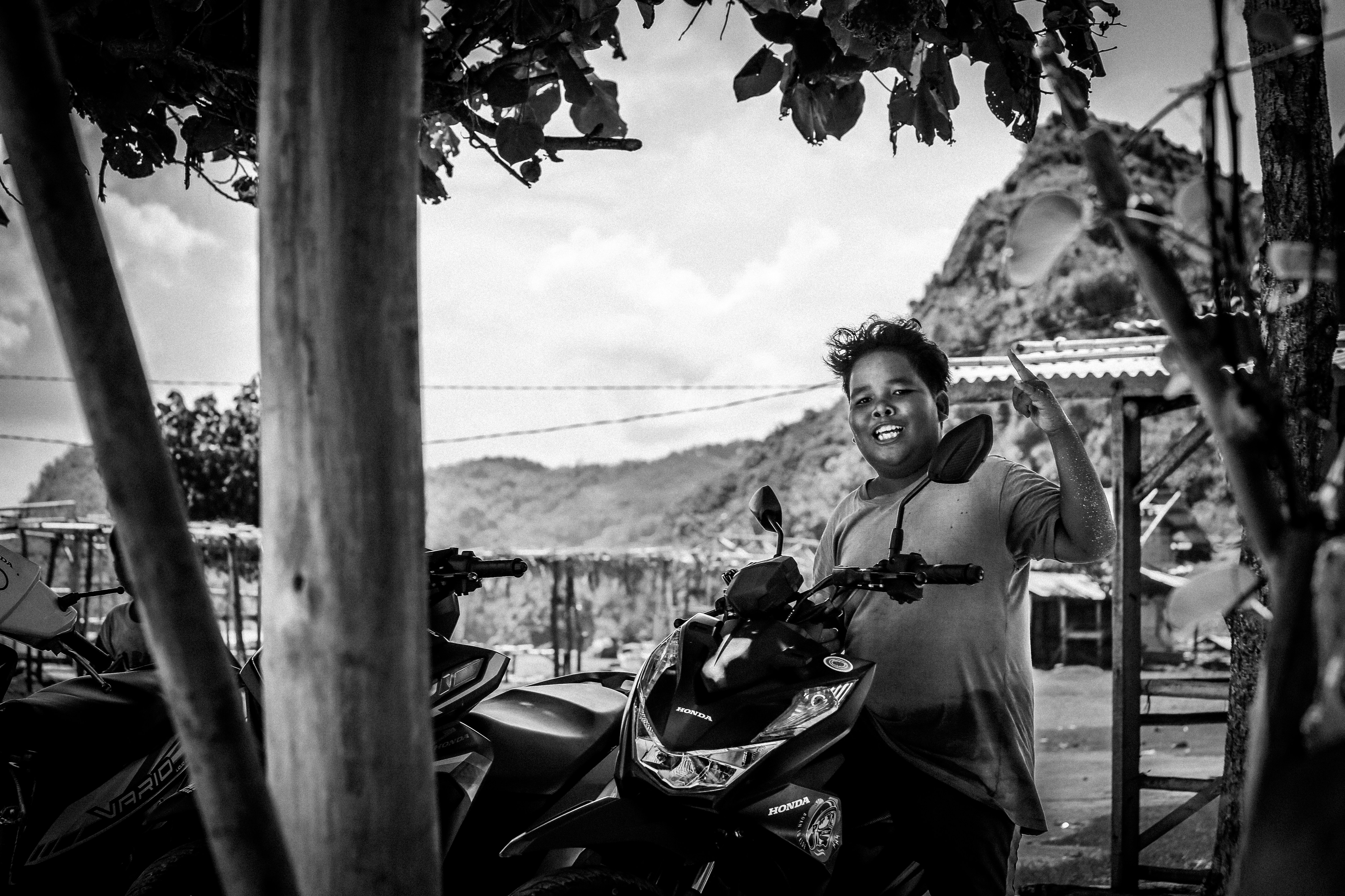 A black and white photo of a man standing next to a motorcycle