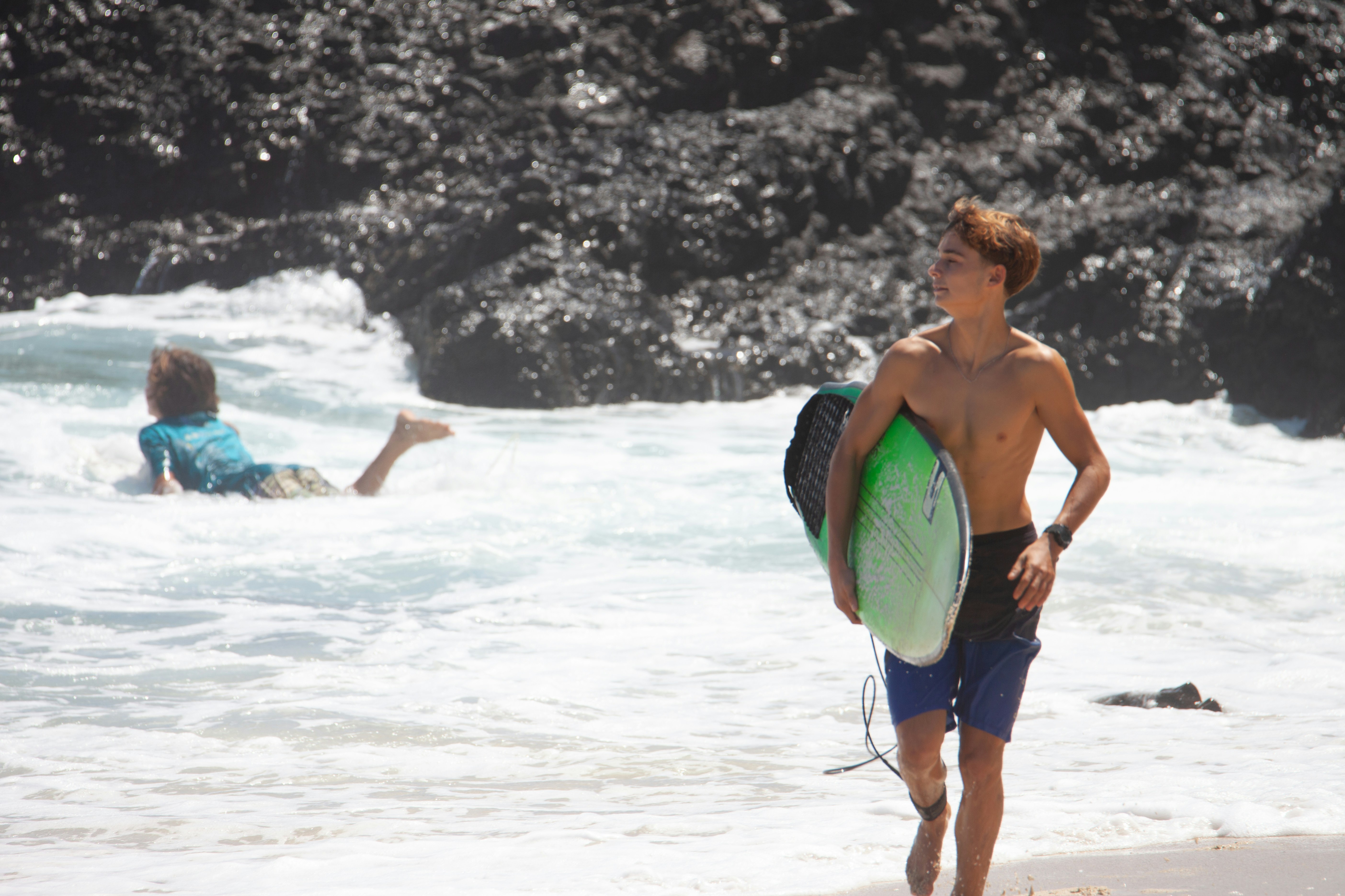 A man standing on a beach holding a surfboard