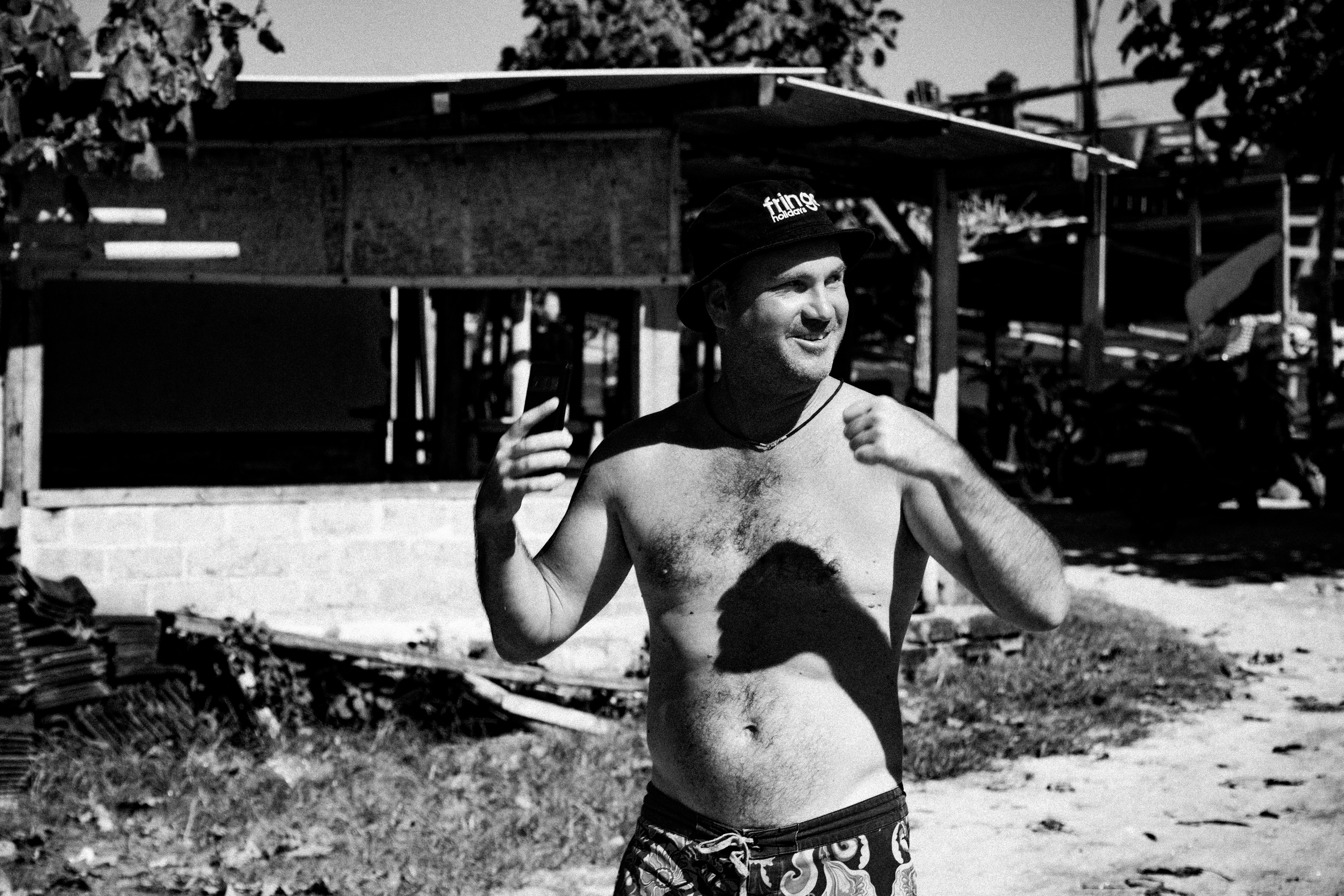 A man in a bathing suit holding a cell phone