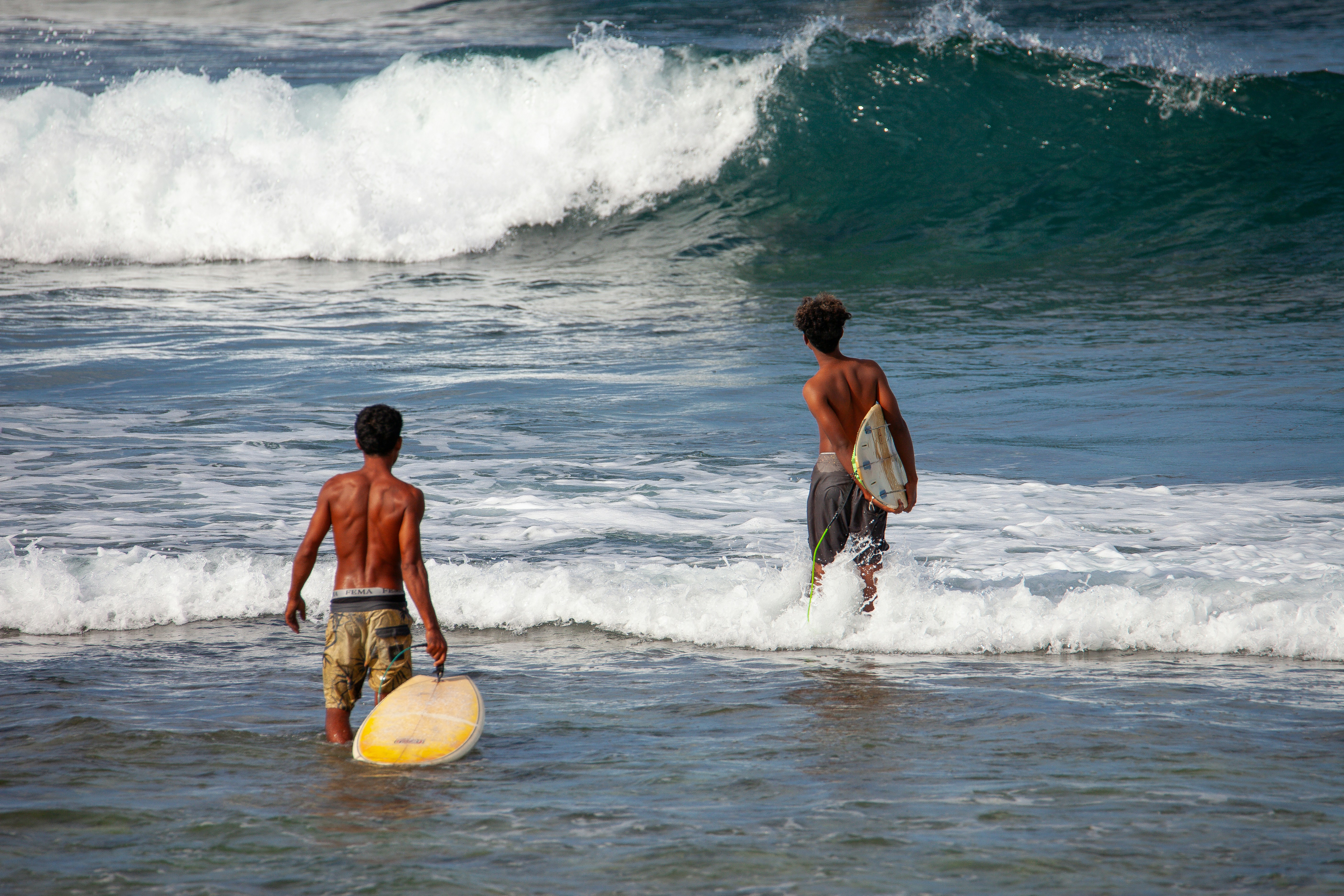 A couple of people that are in the water with surfboards