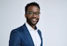 A man in a suit and glasses smiling