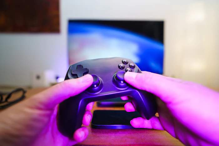 Hands holding a game controller with a TV in the background