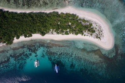 An aerial view of two boats in the water near an island