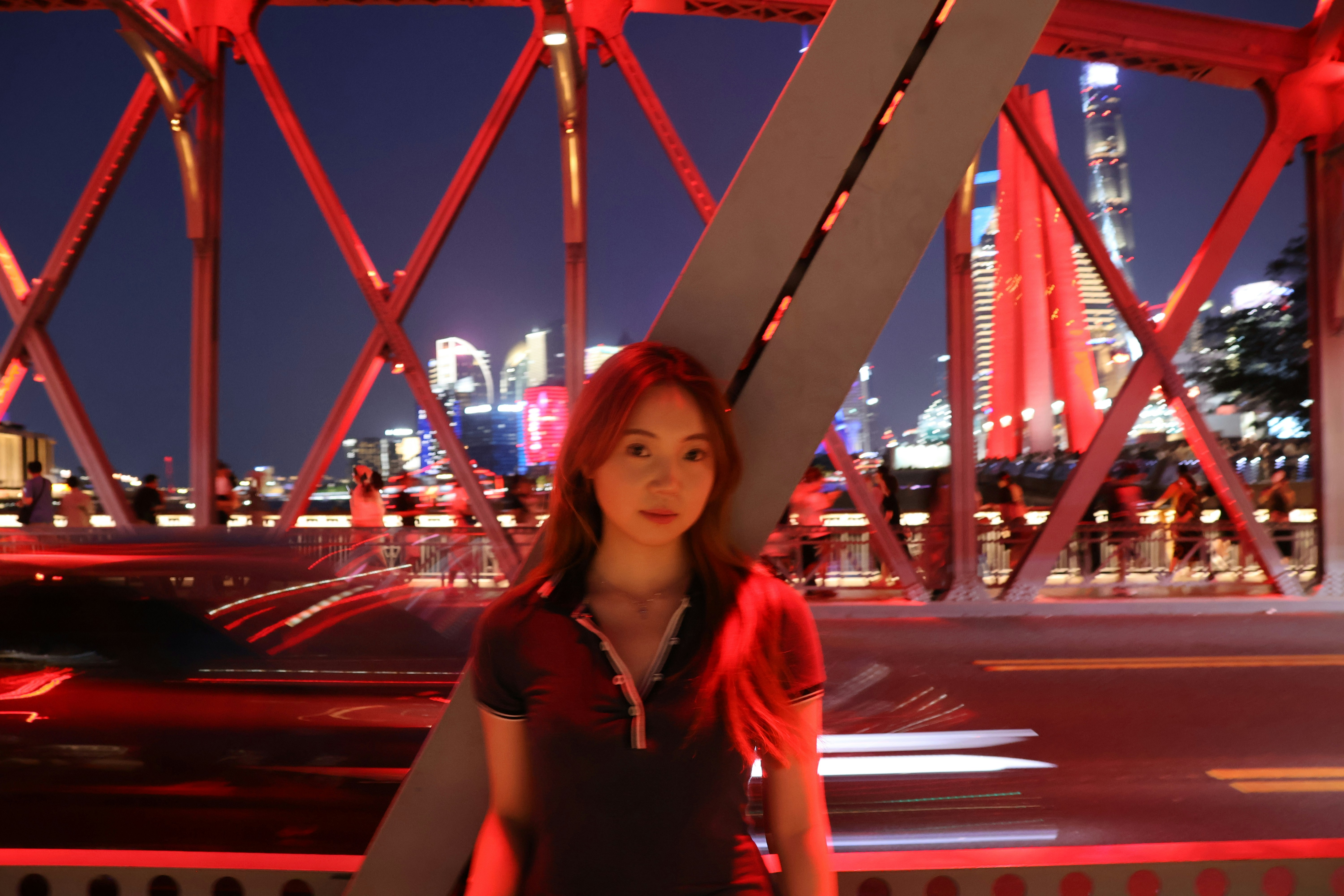 A woman standing in front of a bridge at night