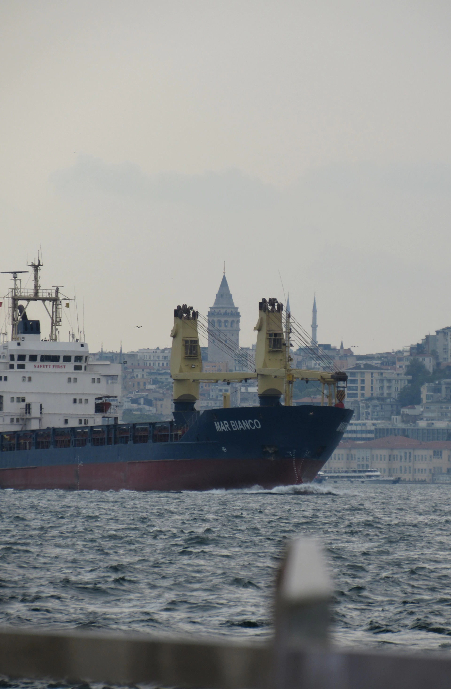 A large boat in the water near a city