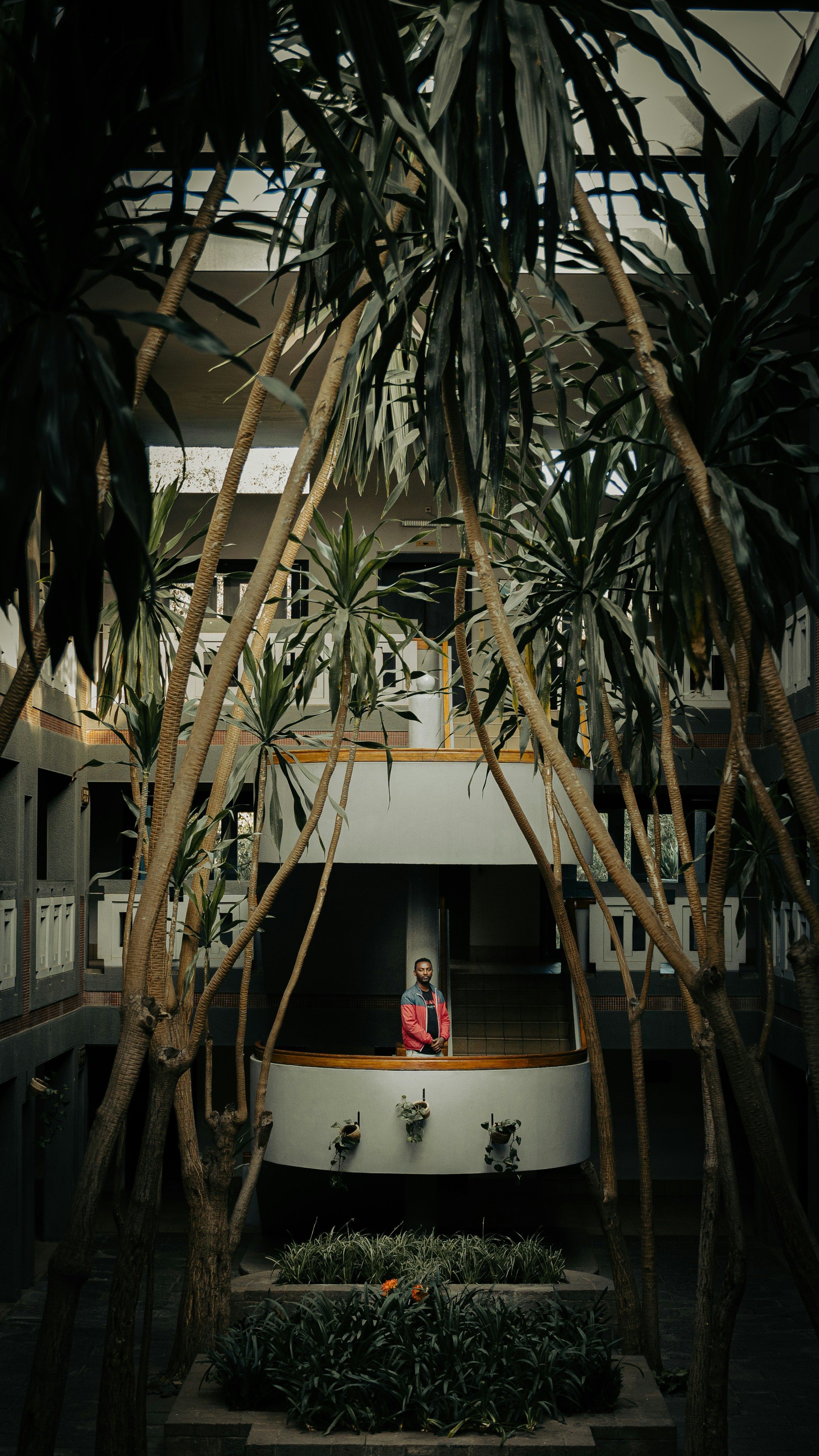 A woman standing in the middle of a building surrounded by palm trees