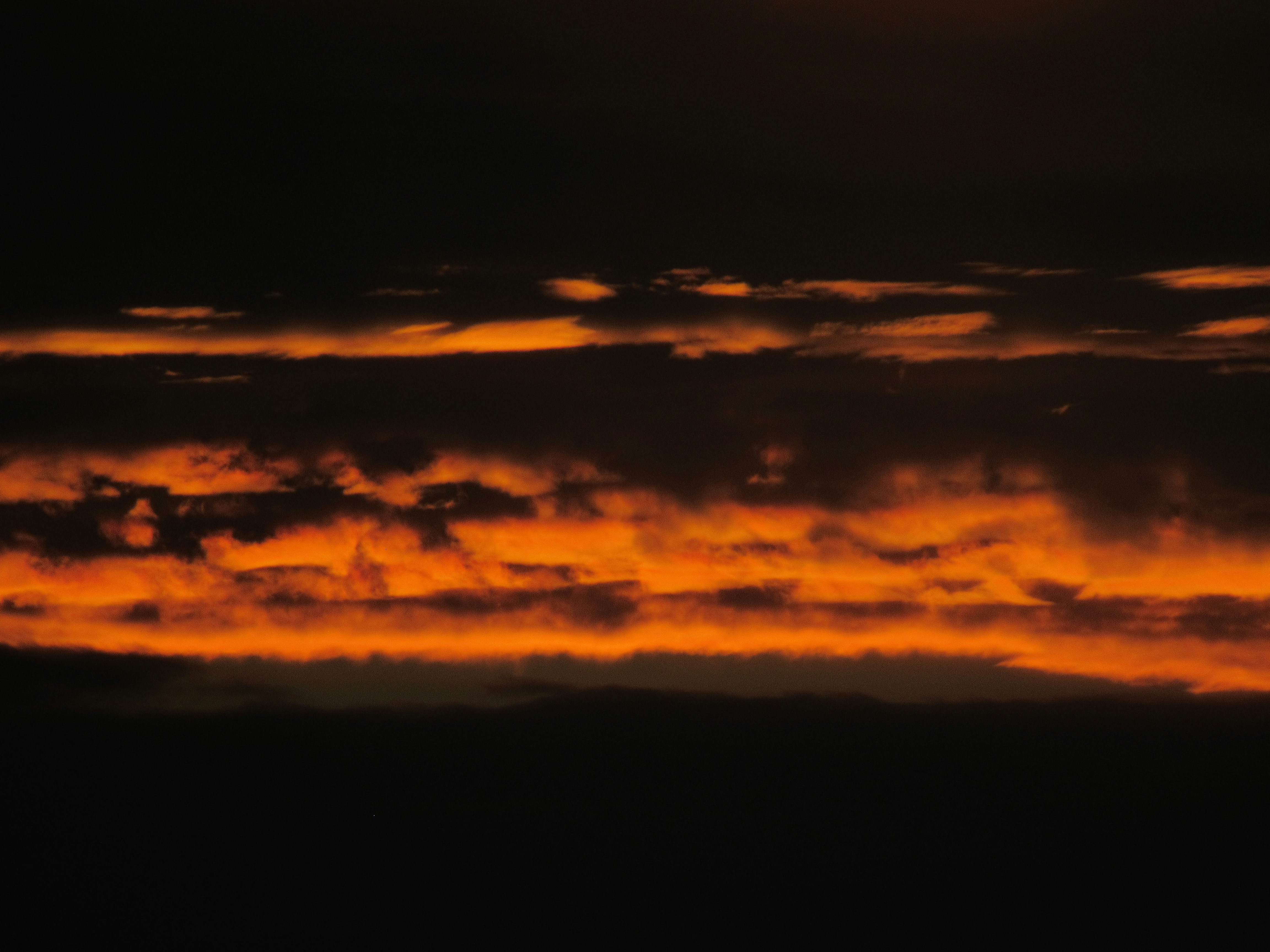 The sun is setting over the clouds in the sky