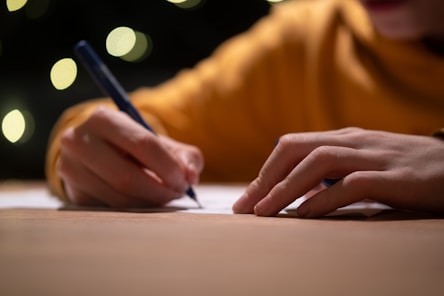 A person writing on a piece of paper with a pen