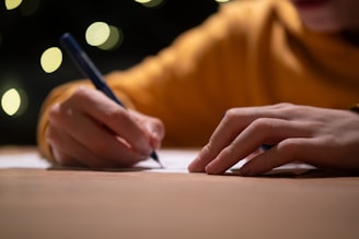 A person writing on a piece of paper with a pen