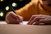 A person writing on a piece of paper with a pen