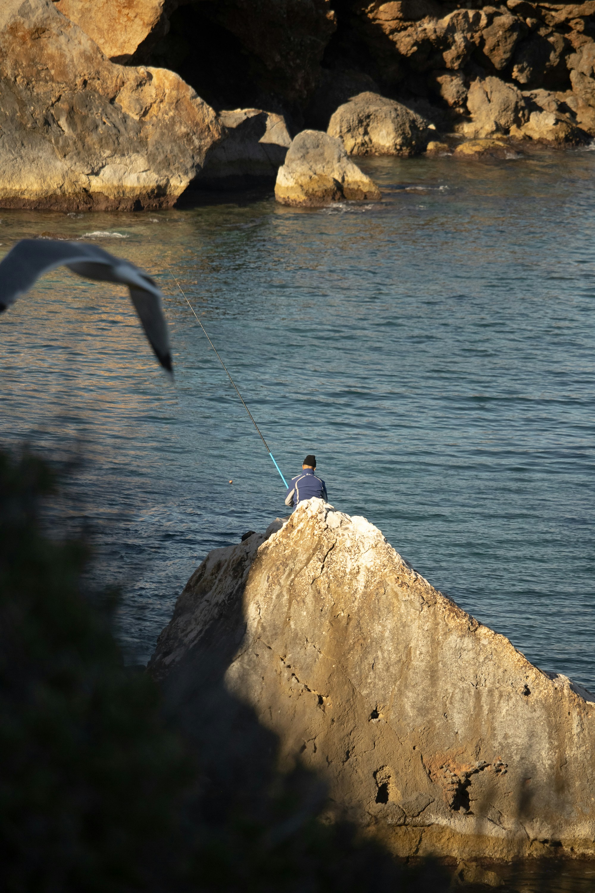 A person sitting on a rock near the water