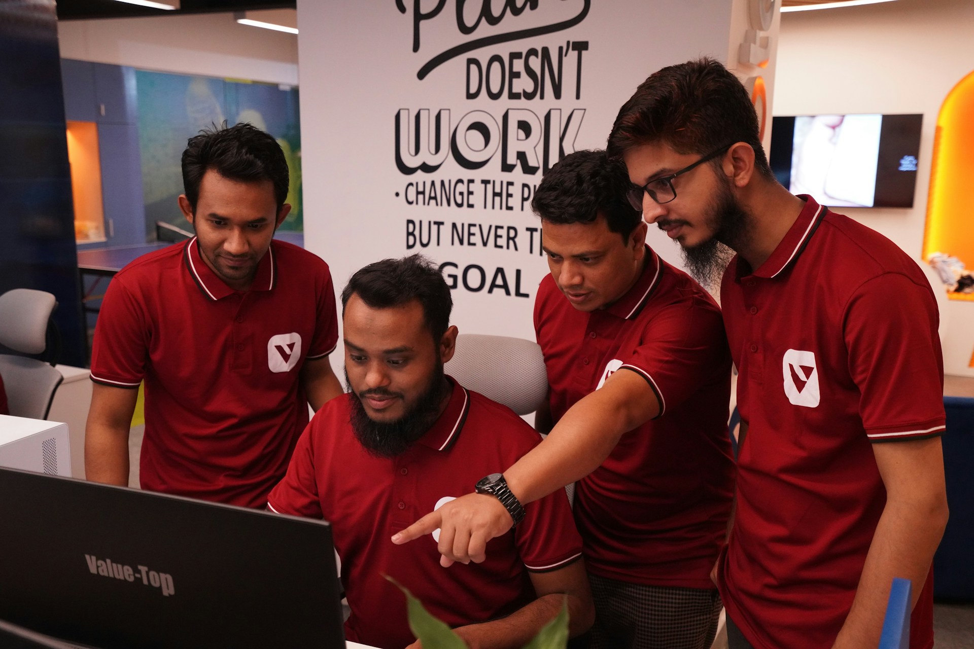A group of men standing around a laptop computer