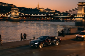 A black car driving down a street next to a bridge