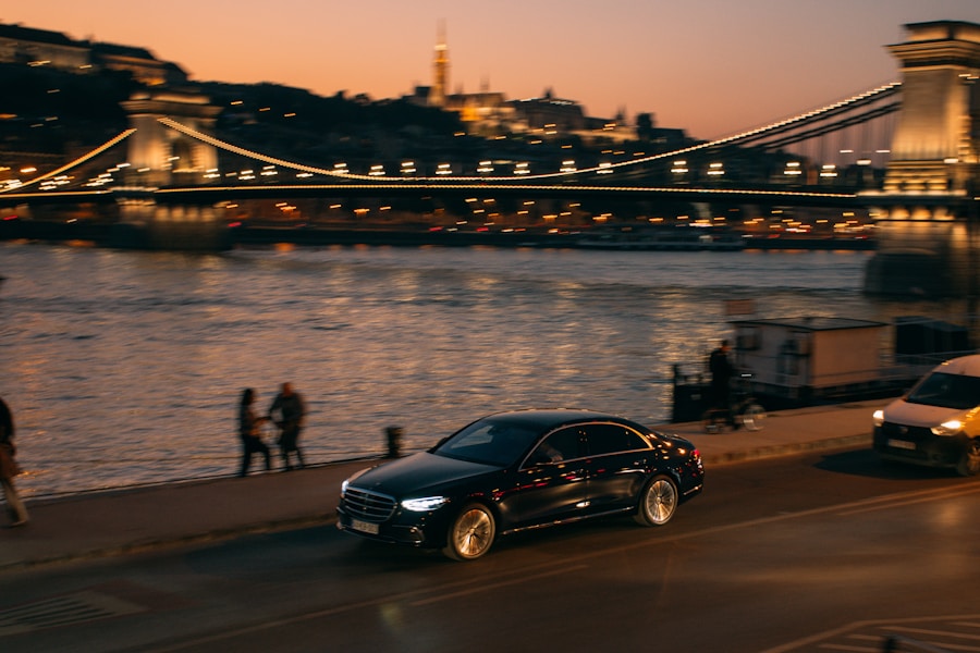 A black car driving down a street next to a bridge