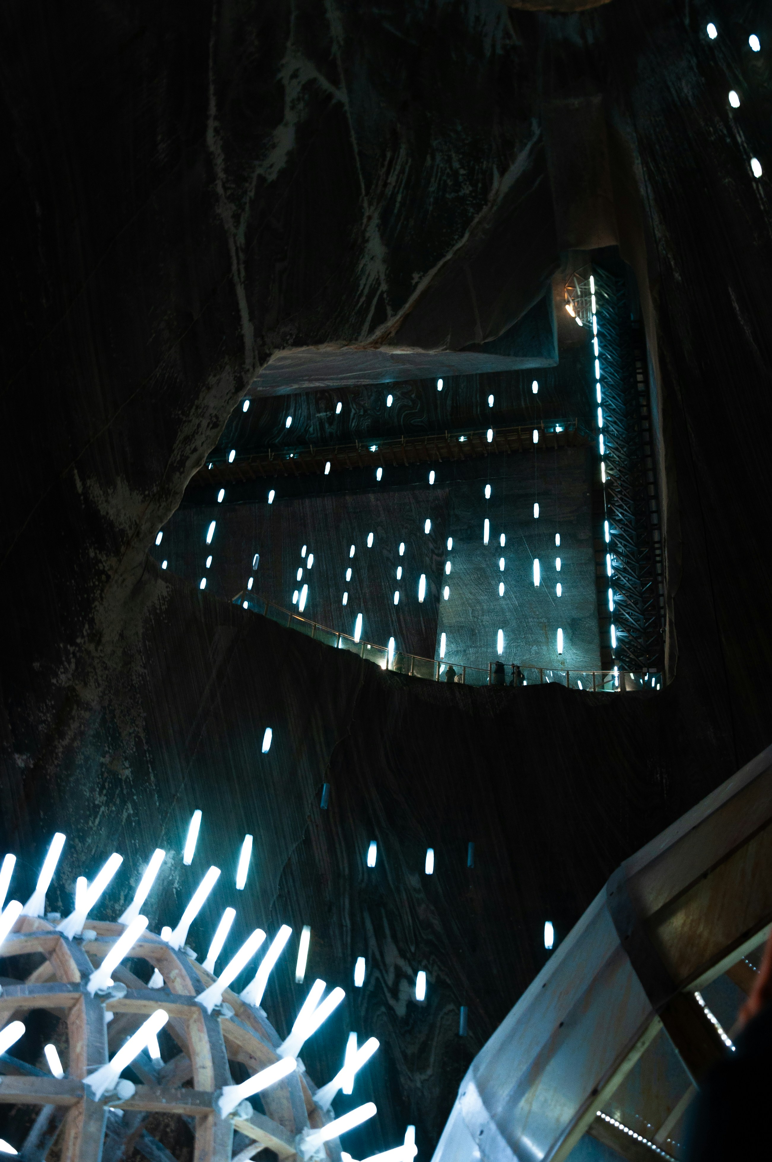 Des gens explorent des sentiers dans une grande caverne souterraine illuminée.