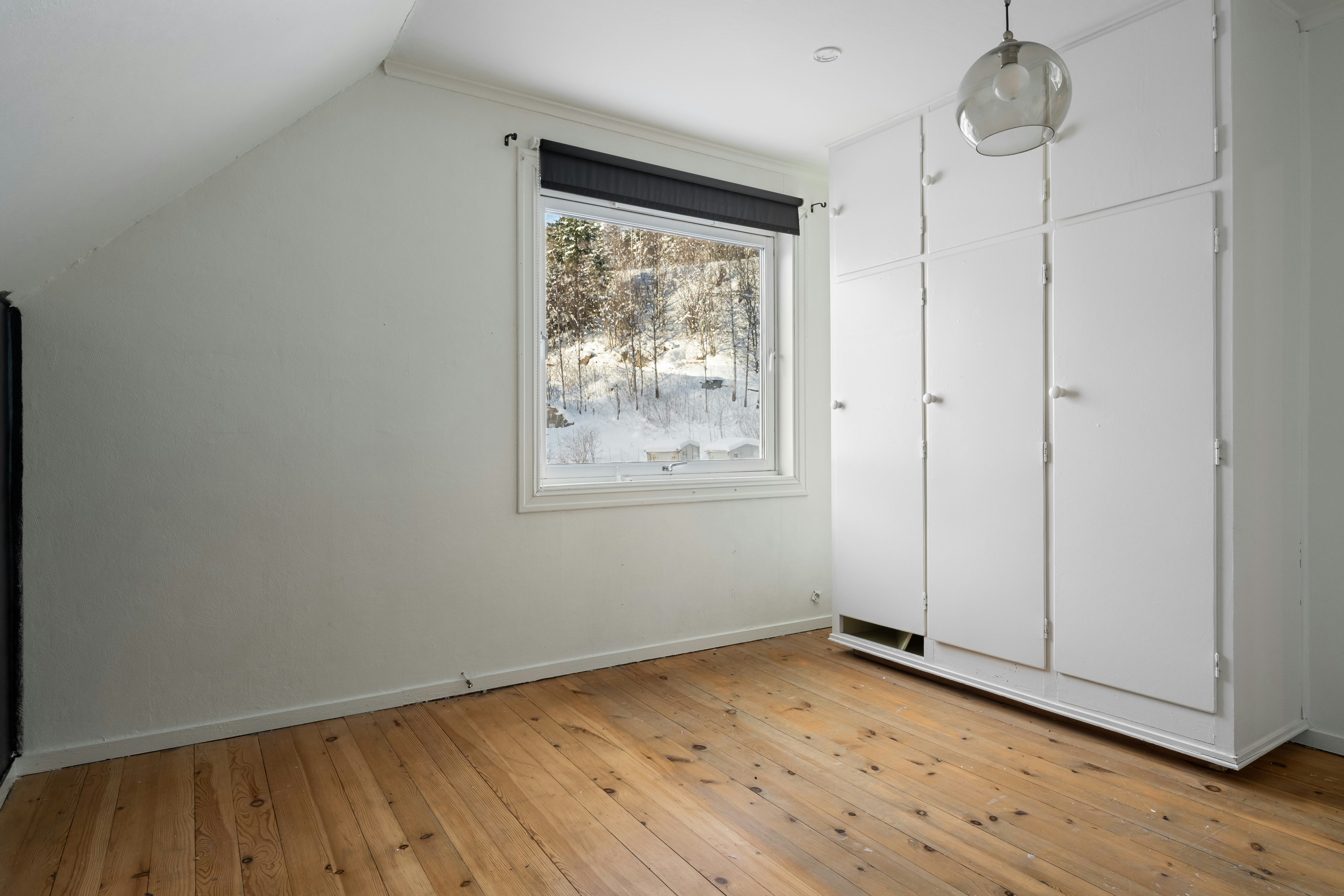 An empty room with a large window and a wooden floor