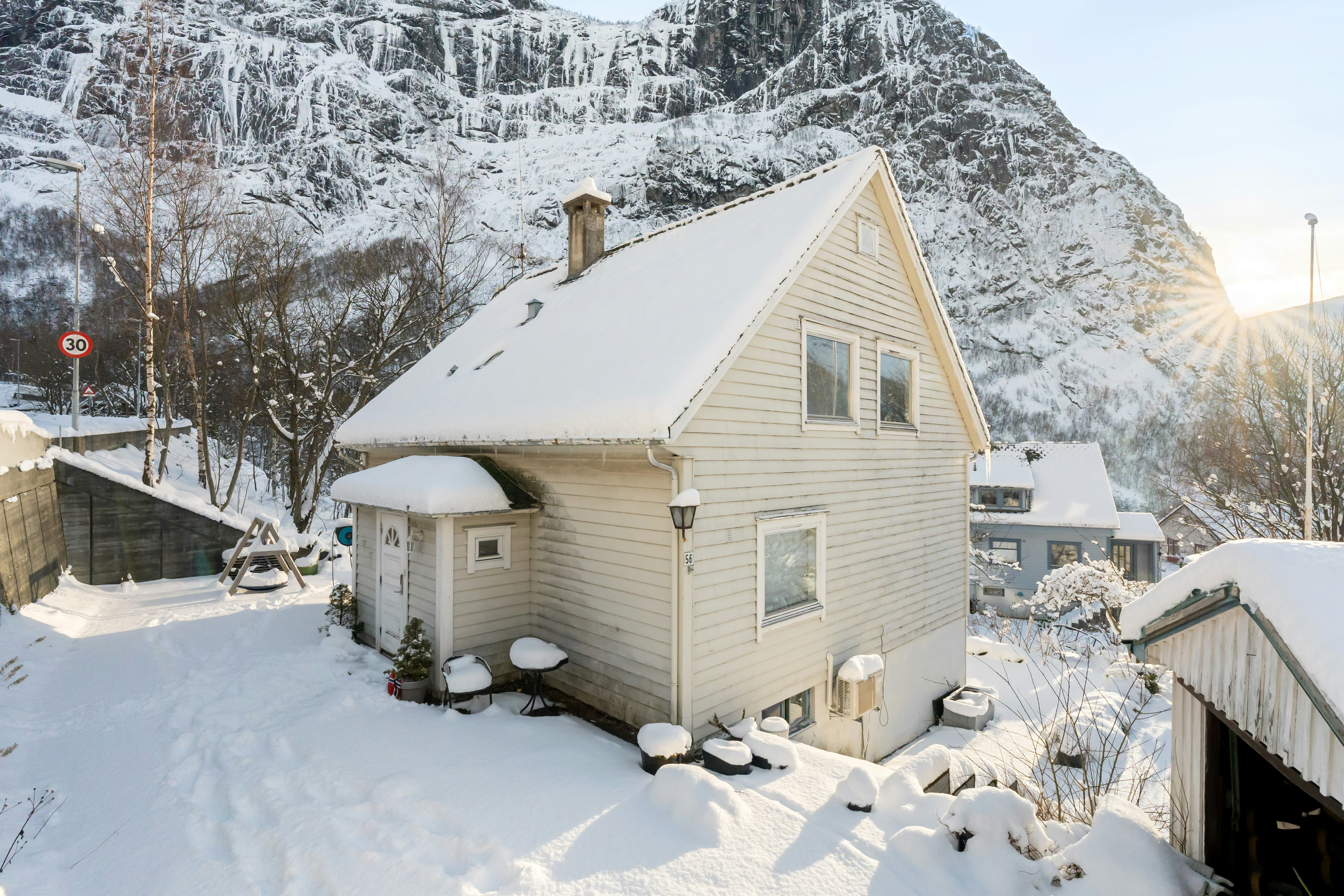 A house covered in snow next to a mountain