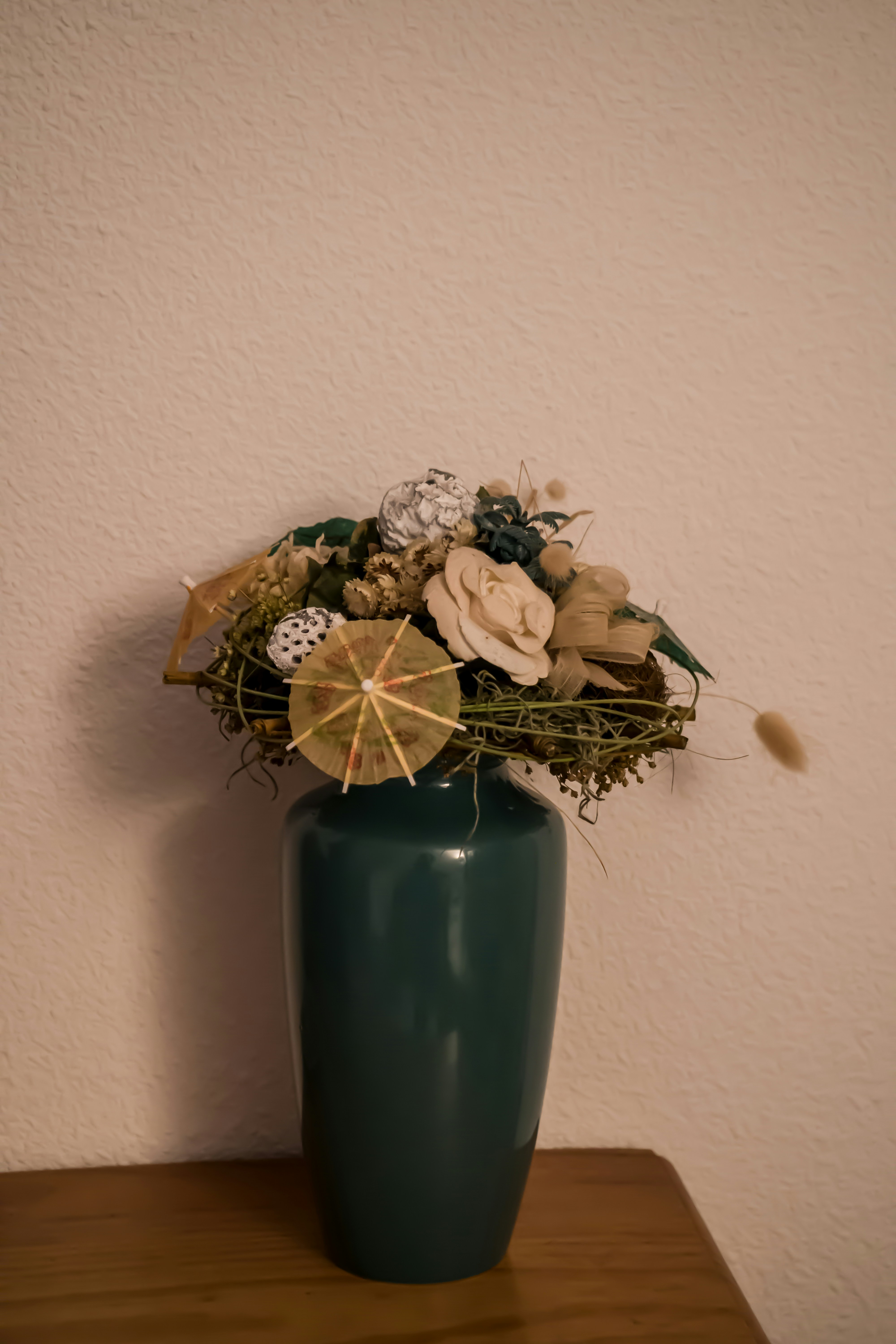 A green vase filled with flowers on top of a wooden table