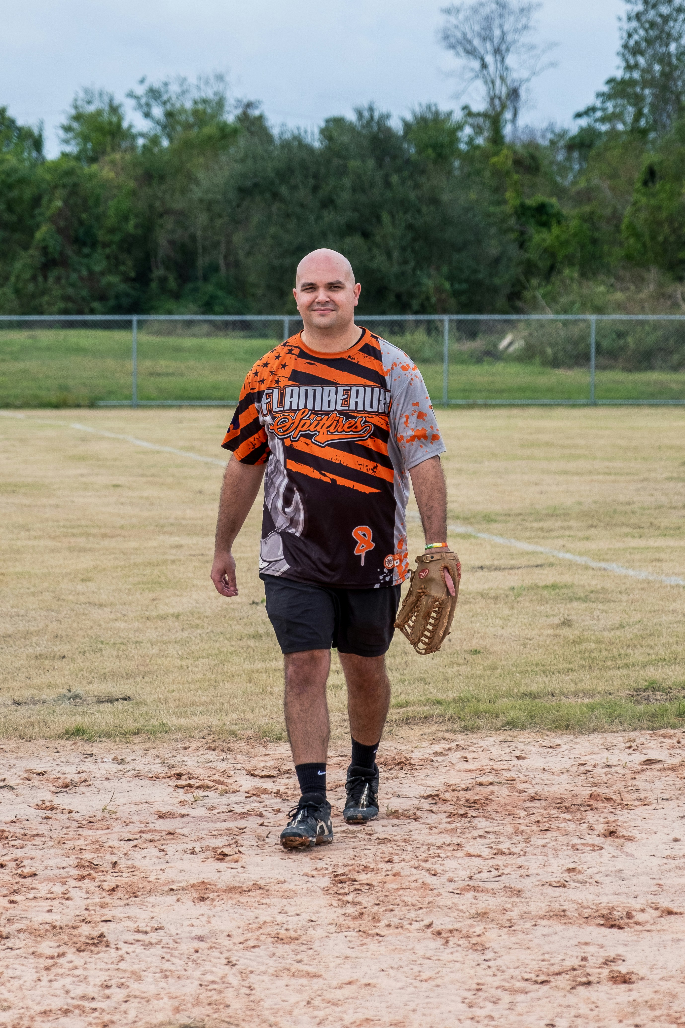 A man in a catchers mitt walking on a baseball field