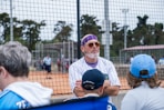 A group of people standing around a baseball field