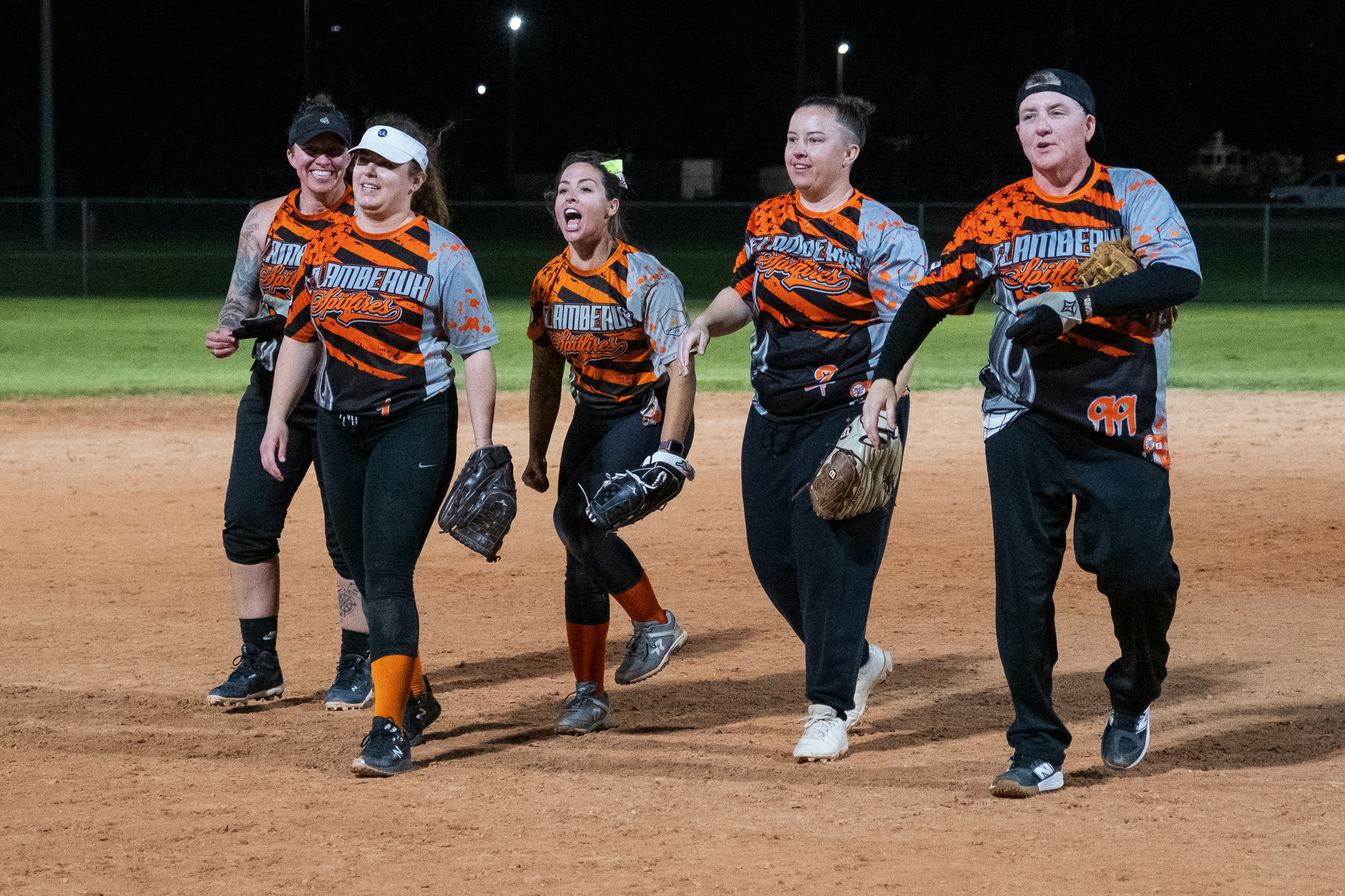 A group of young women walking across a baseball field