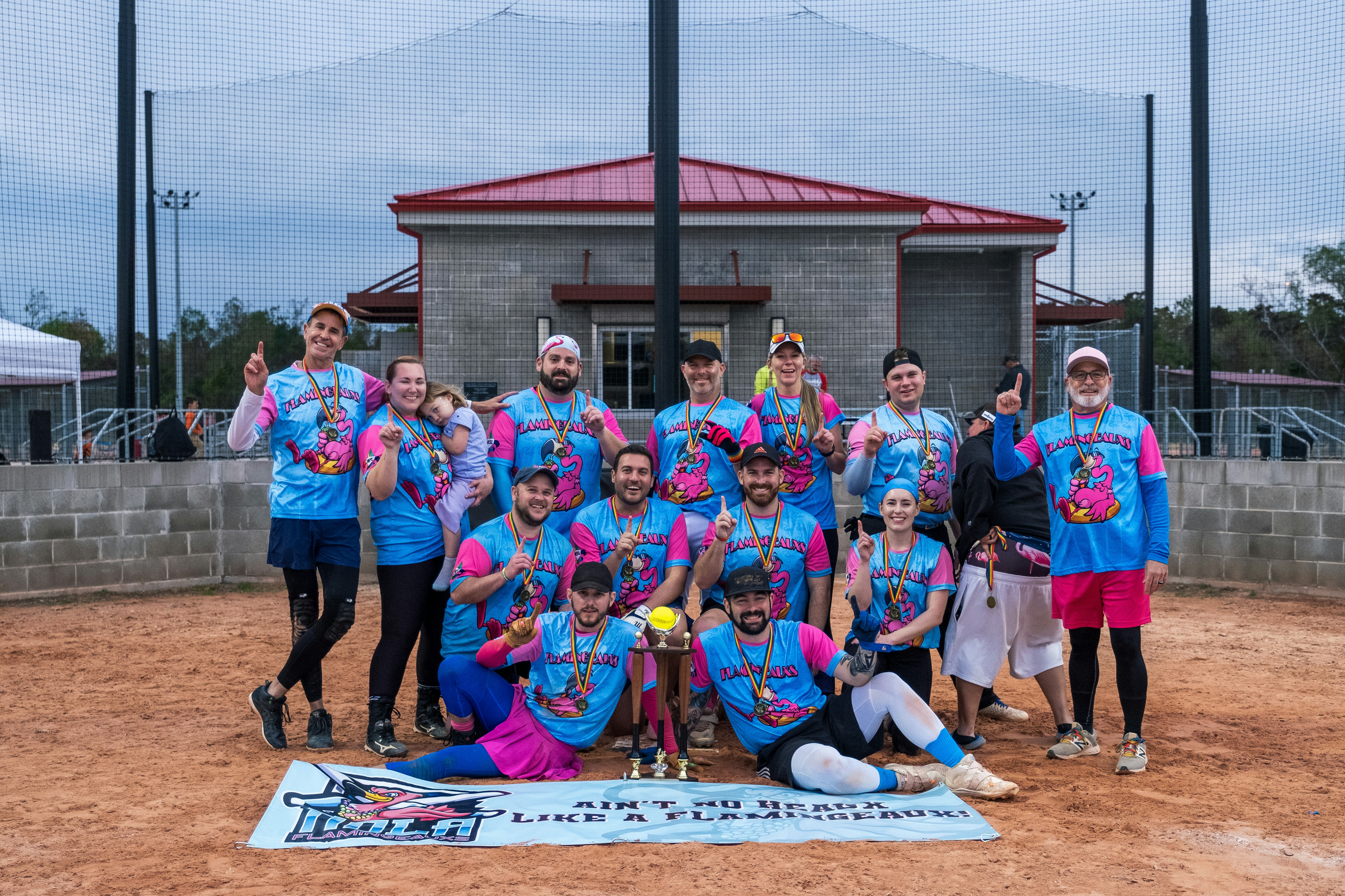 A group of volunteers wearing matching shirts smiling together at a community event, holding a banner that says thank you