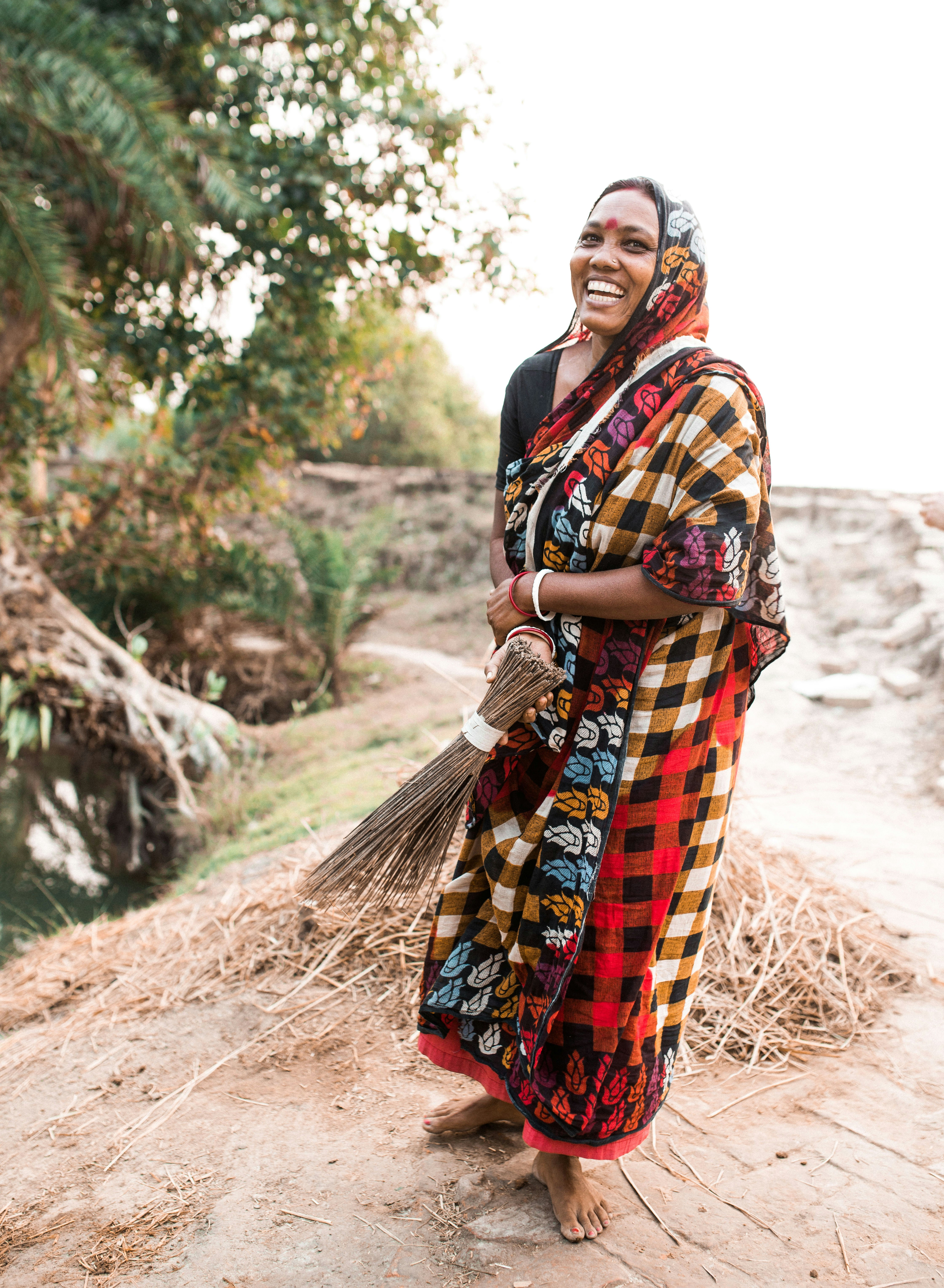 A woman standing on a dirt road next to a river