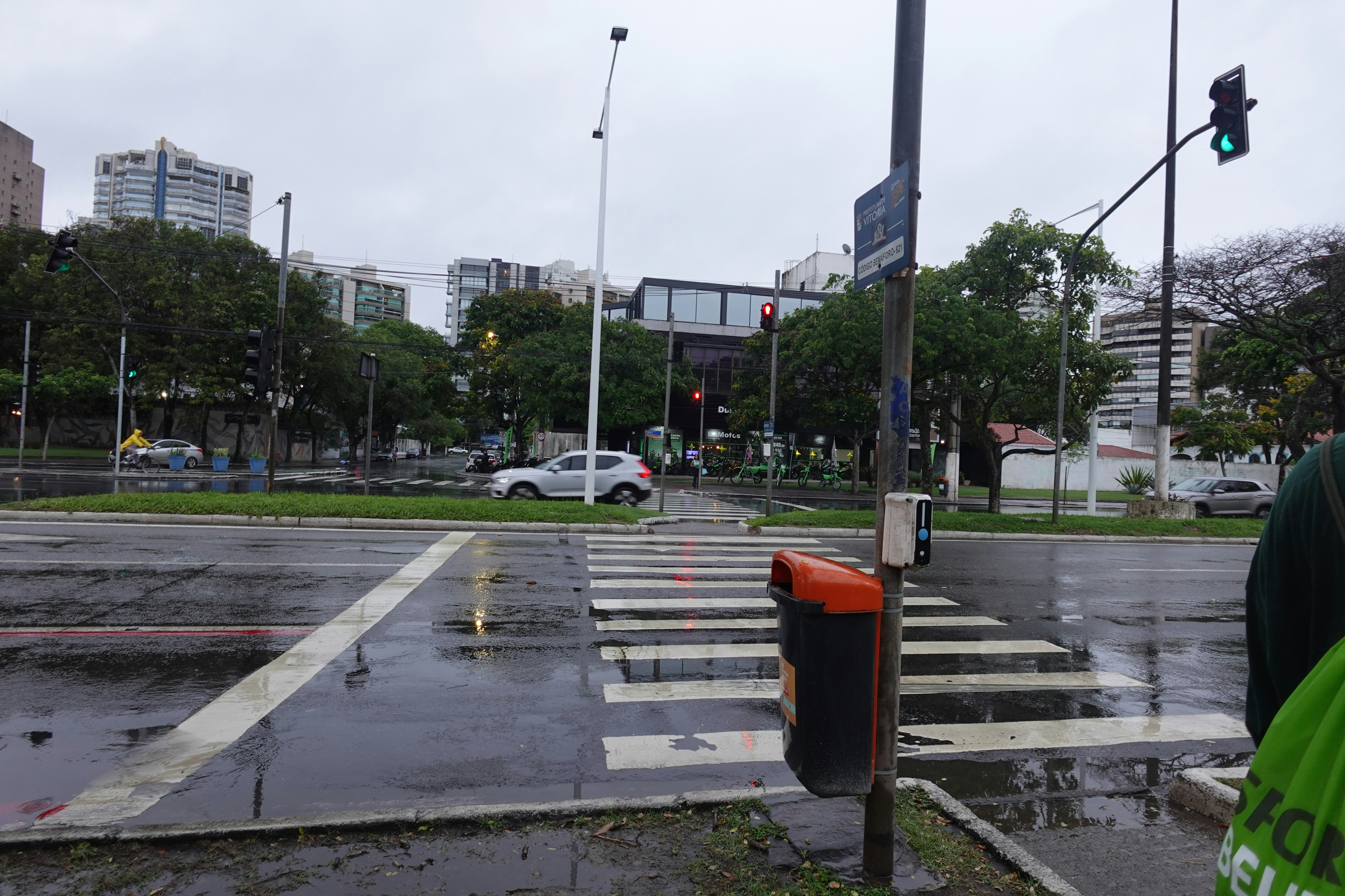 A man standing at a crosswalk in the rain