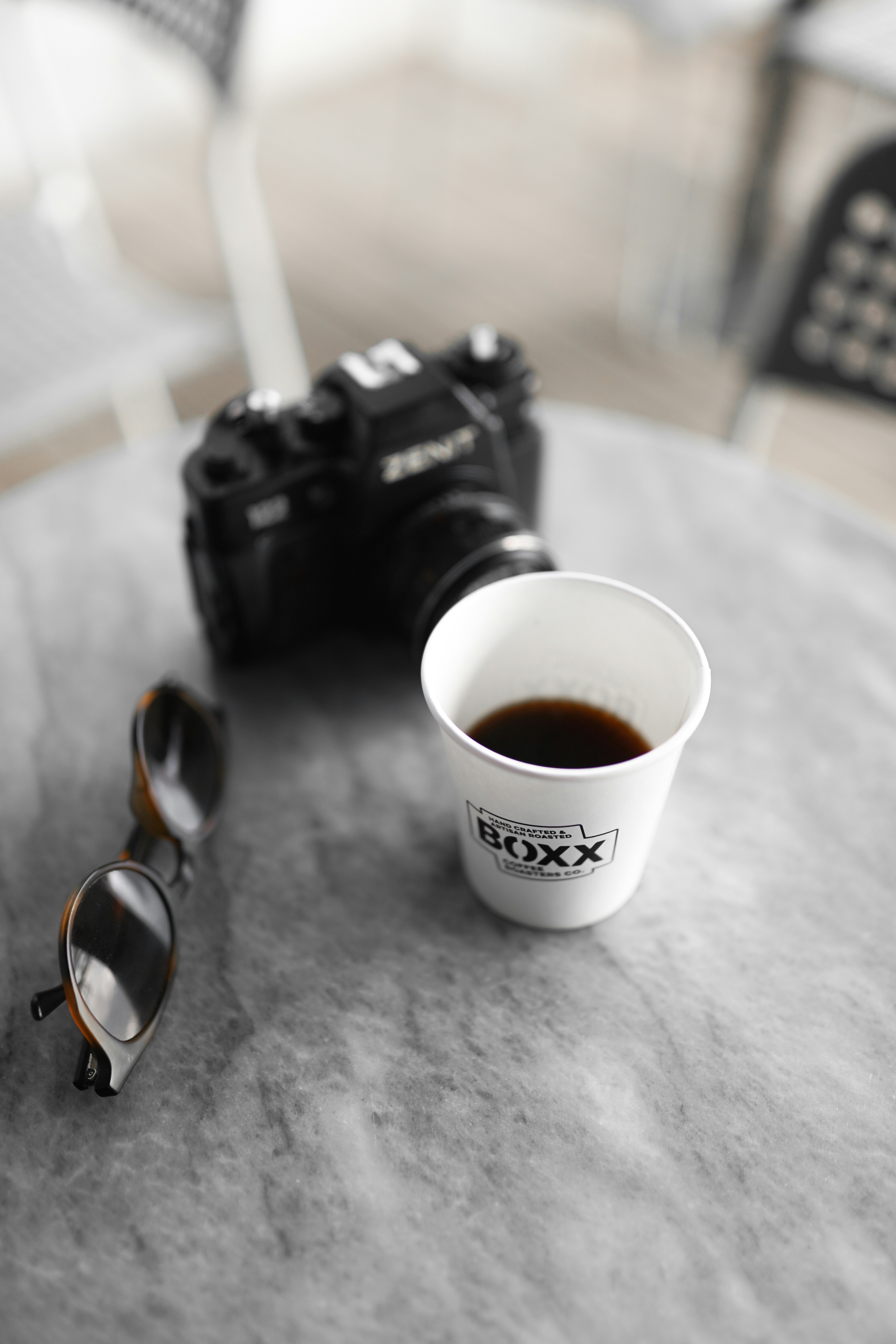 A cup of coffee sitting on top of a table next to a camera