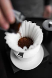 A person pours coffee into a white cup